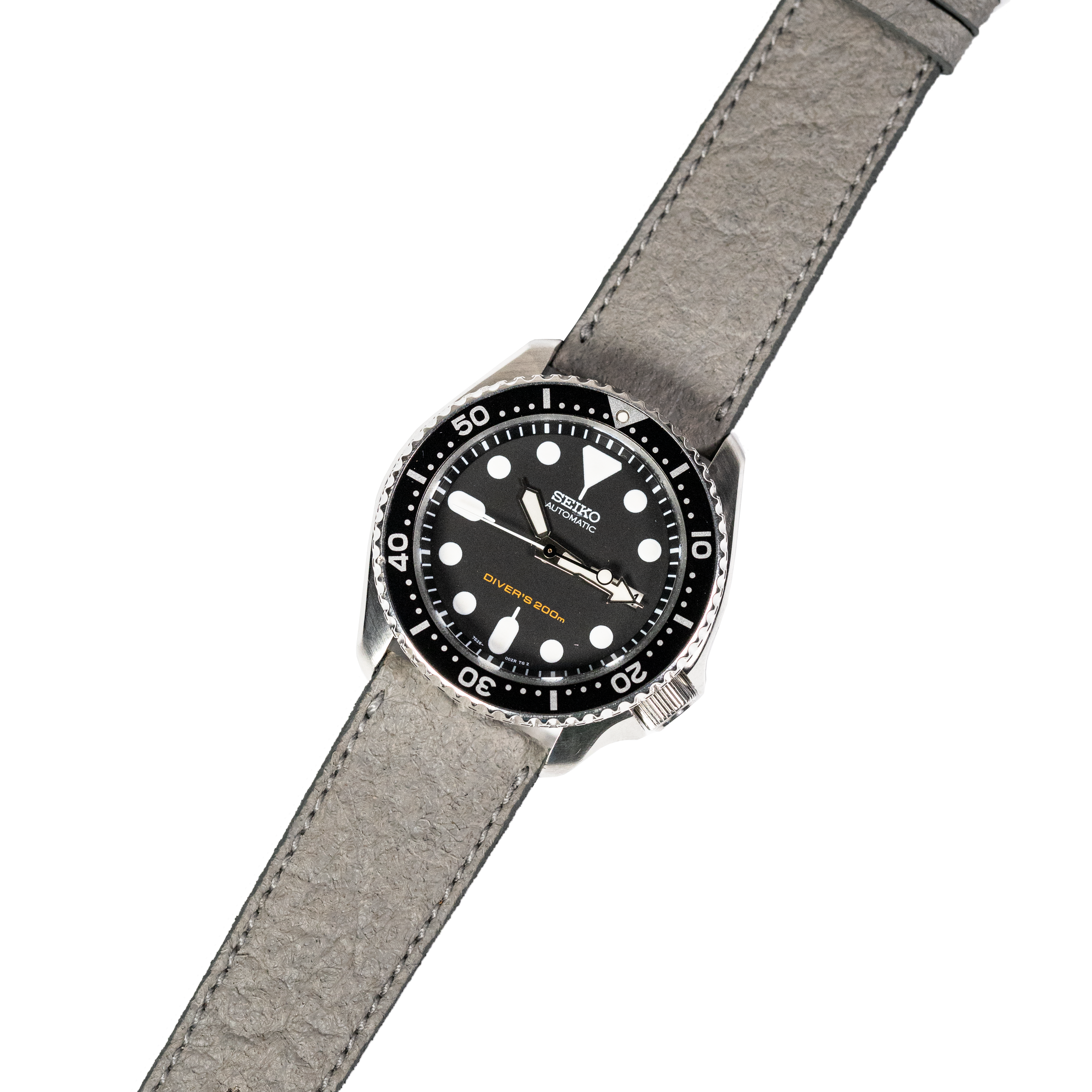 Seiko Prospex automatic dive watch with black dial, white dot markers, rotating bezel, and grey suede leather strap