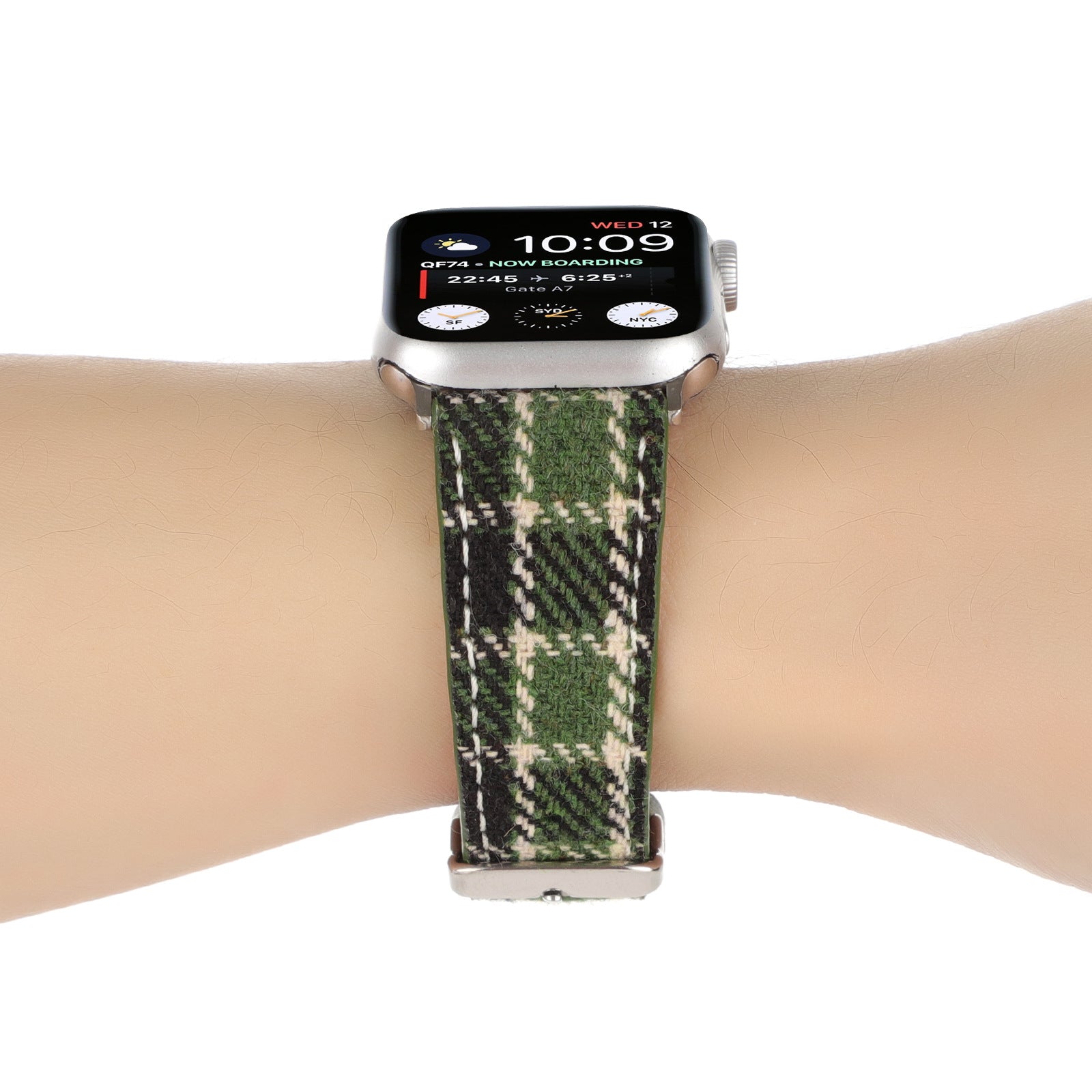Silver smartwatch with green plaid woven fabric band worn on wrist, displaying time and flight information on black screen