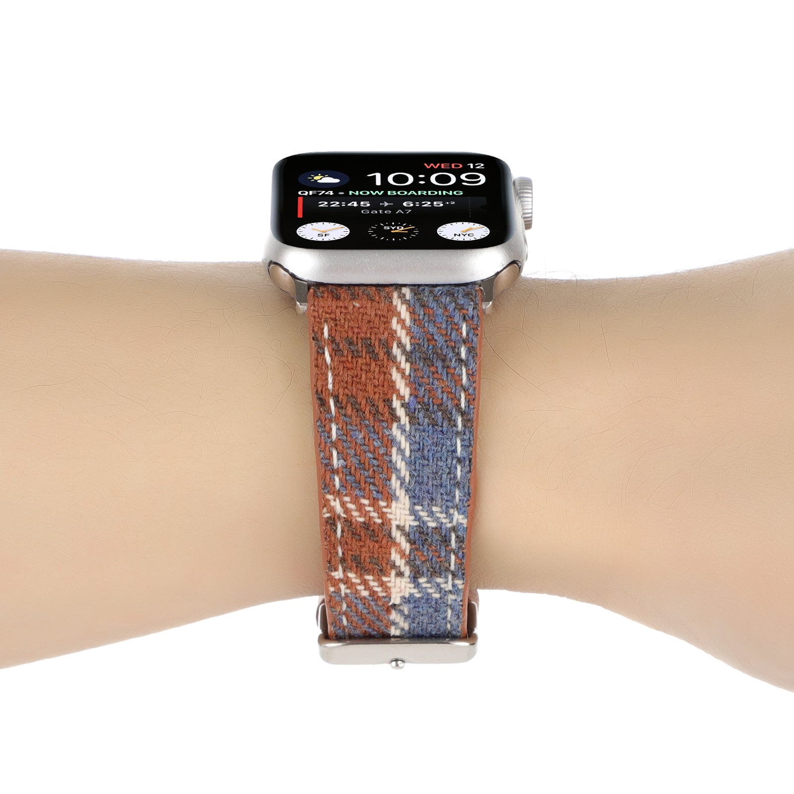 Smart watch with silver aluminum case and plaid woven fabric band in rust, navy and cream, displaying time and flight information on OLED screen