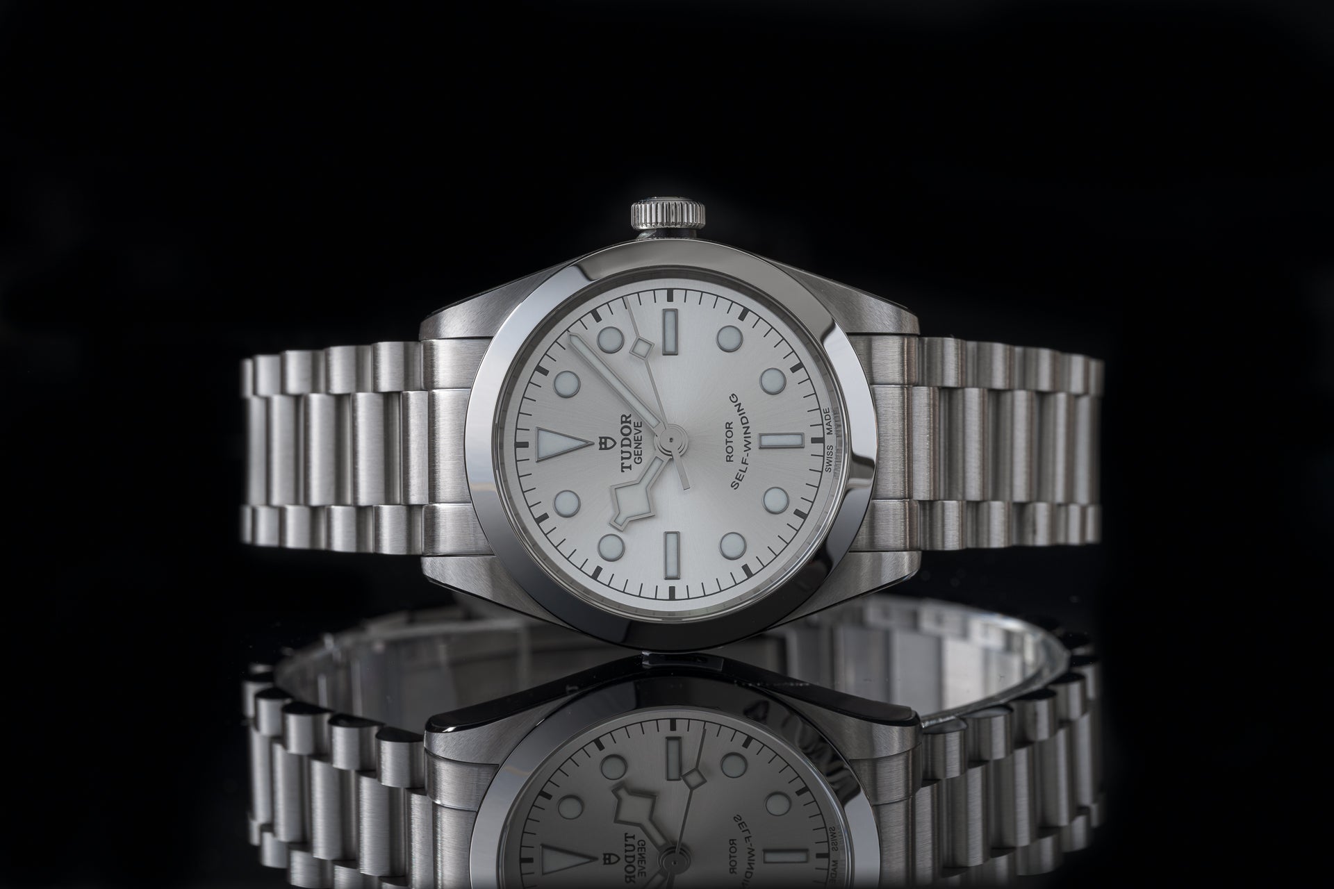 Stainless steel Tudor Black Bay 36 watch with silver dial and matching metal bracelet on black background