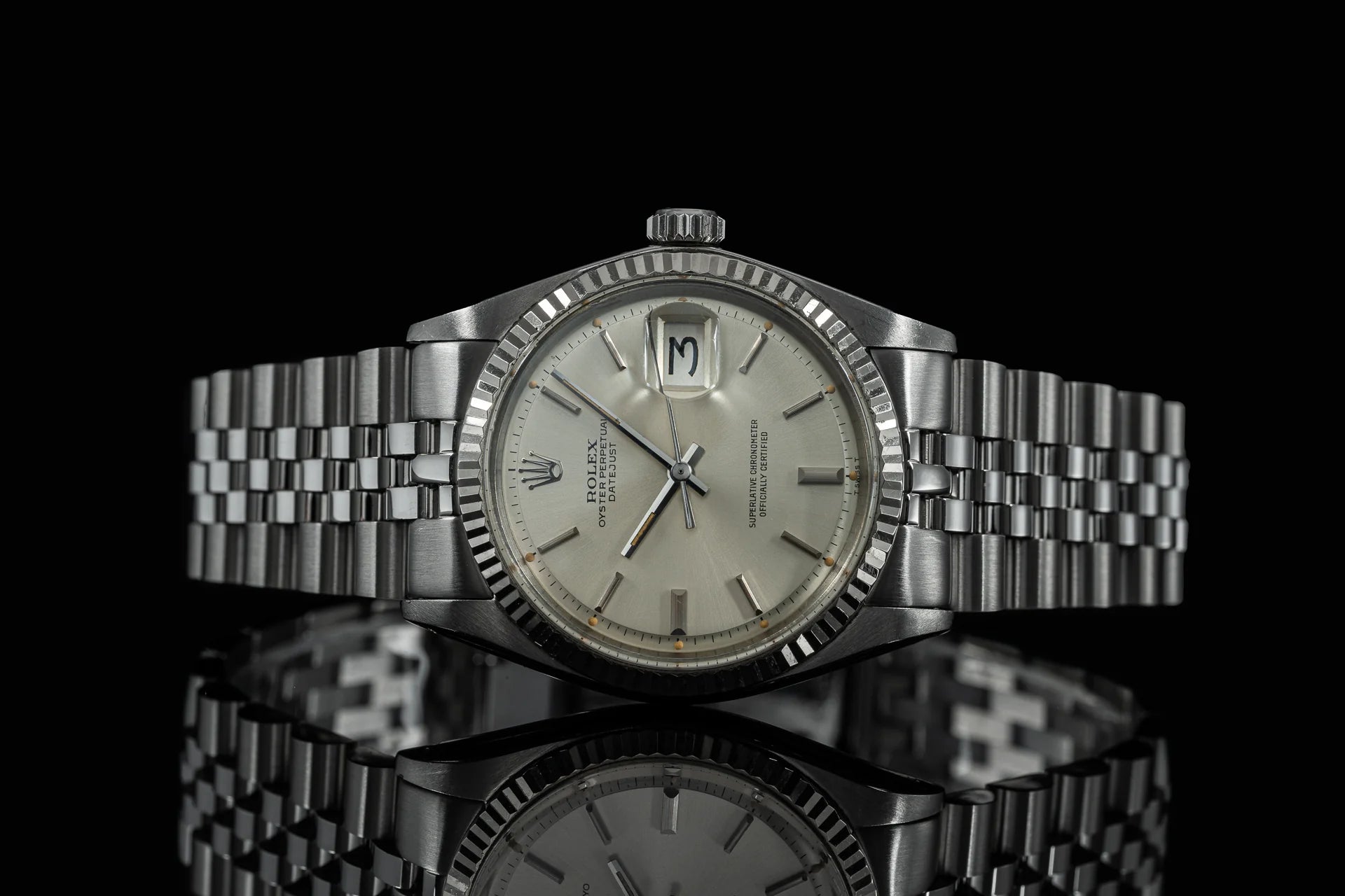 Vintage Rolex Datejust stainless steel watch with jubilee bracelet, silver dial, and fluted bezel on black background
