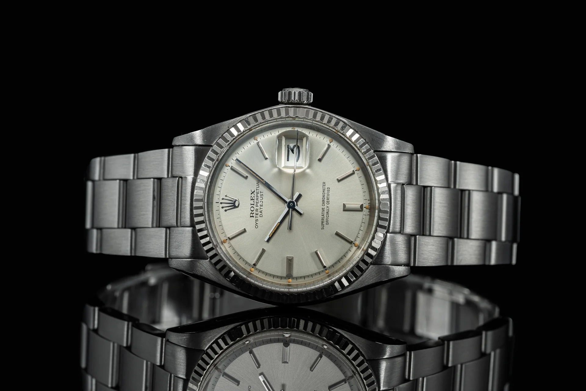 Vintage Rolex Datejust 1601 1603 stainless steel watch with fluted bezel and silver dial on black background