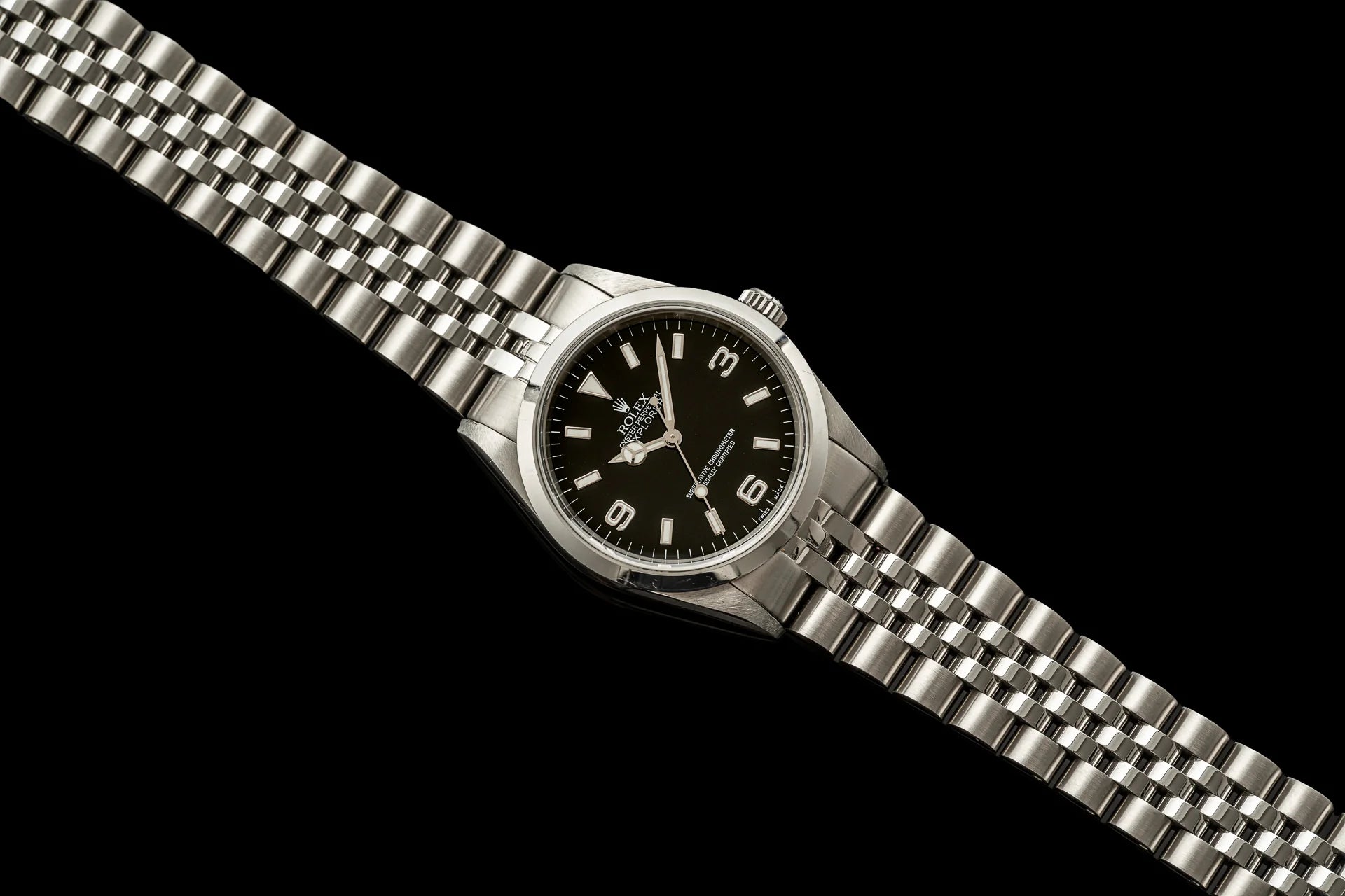 Stainless steel bracelet watch with black dial, Arabic numerals, and polished metal band on black background
