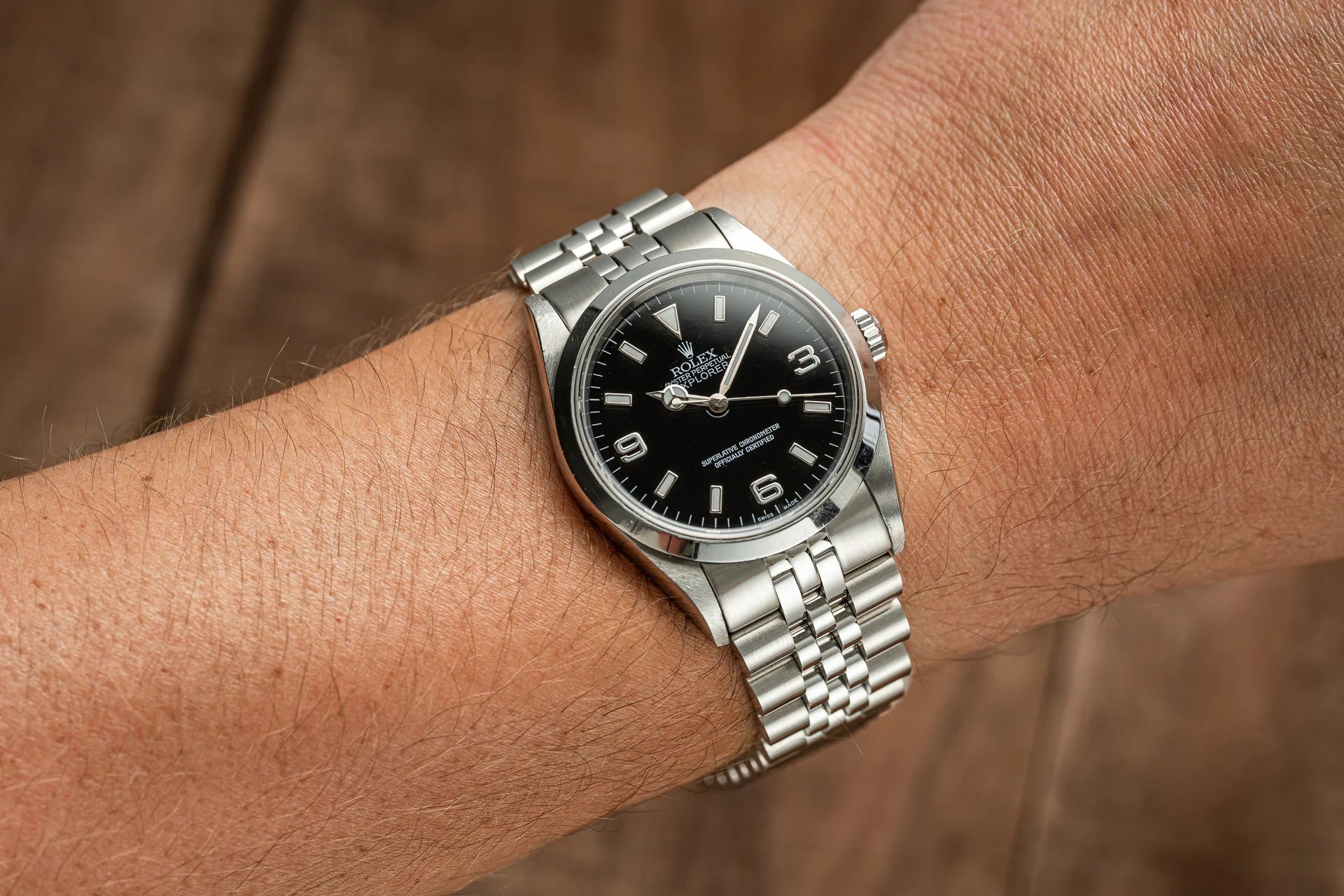 Stainless steel Rolex Explorer watch with black dial and silver bracelet worn on wrist
