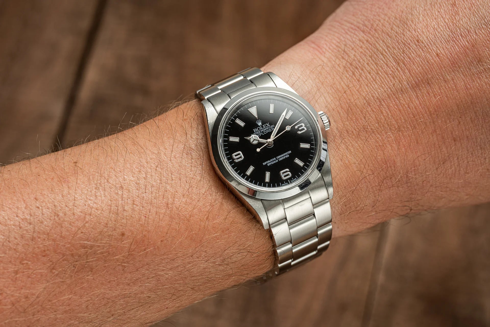 Stainless steel Rolex Explorer watch with black dial and Arabic numerals on wrist with matching bracelet