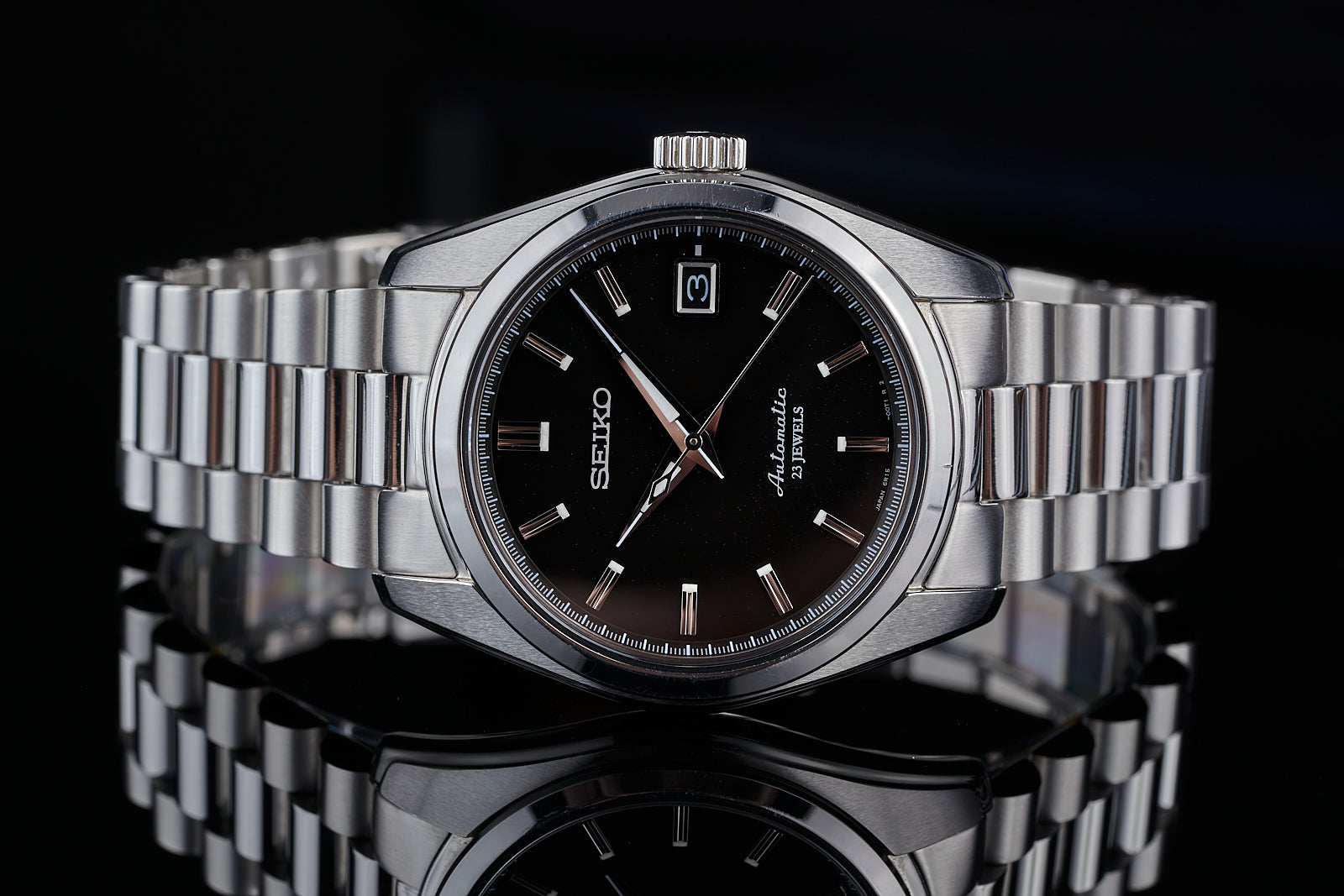 Seiko Prospex stainless steel watch with black dial, date window, and metal bracelet on black background