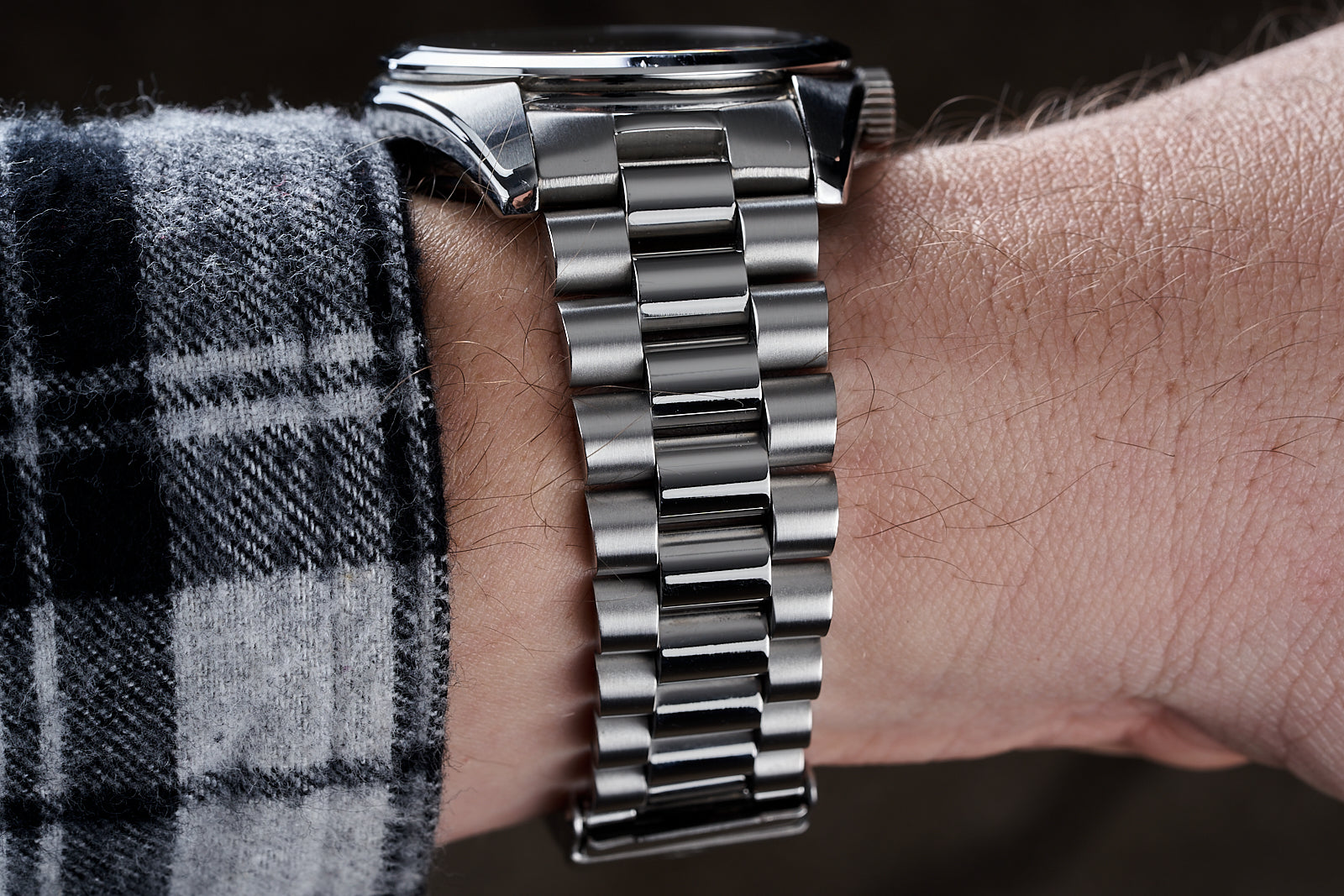 Stainless steel bracelet with solid link design worn on wrist with checked shirt sleeve