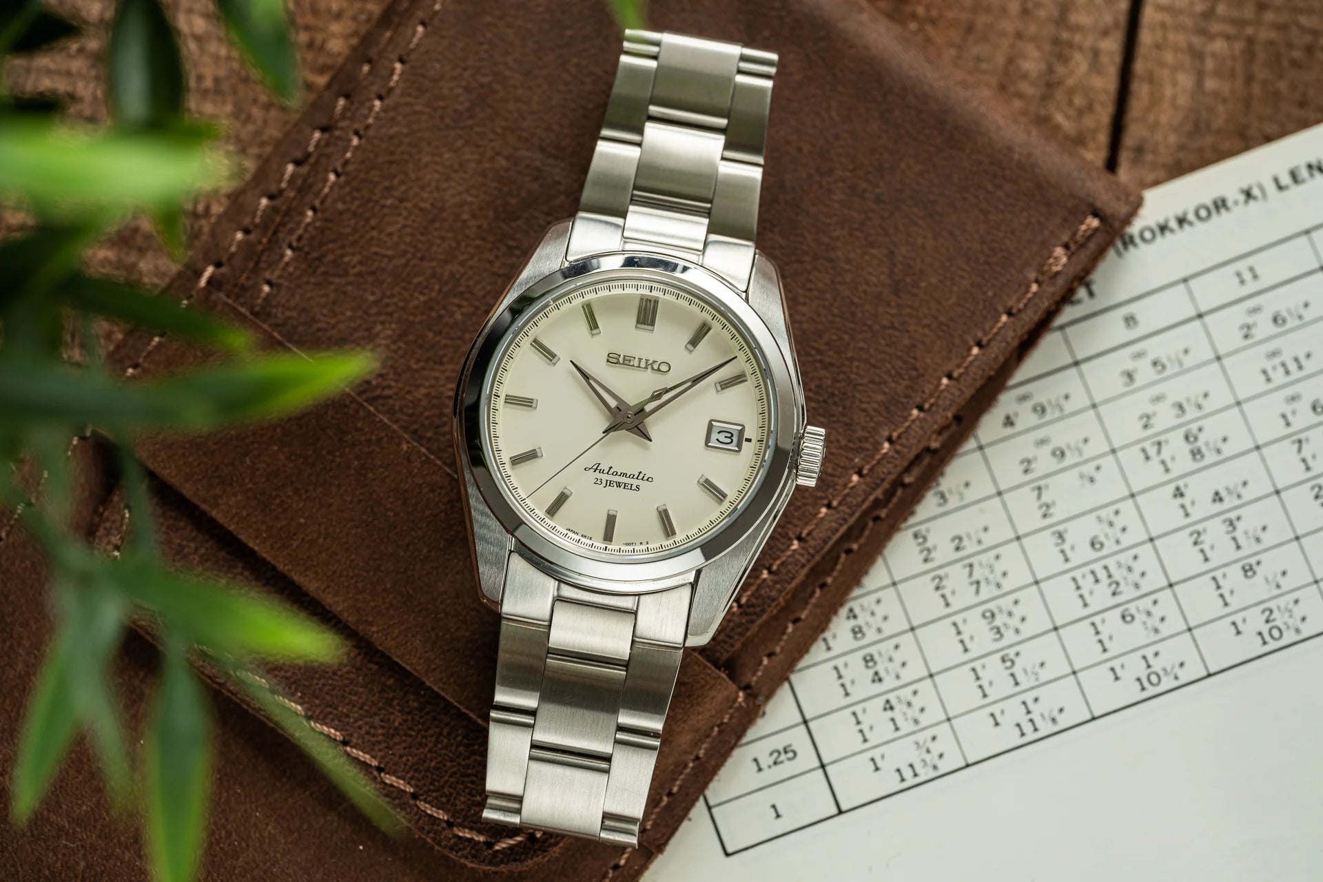 Seiko automatic stainless steel watch with cream dial, date window, and metal bracelet on brown leather strap