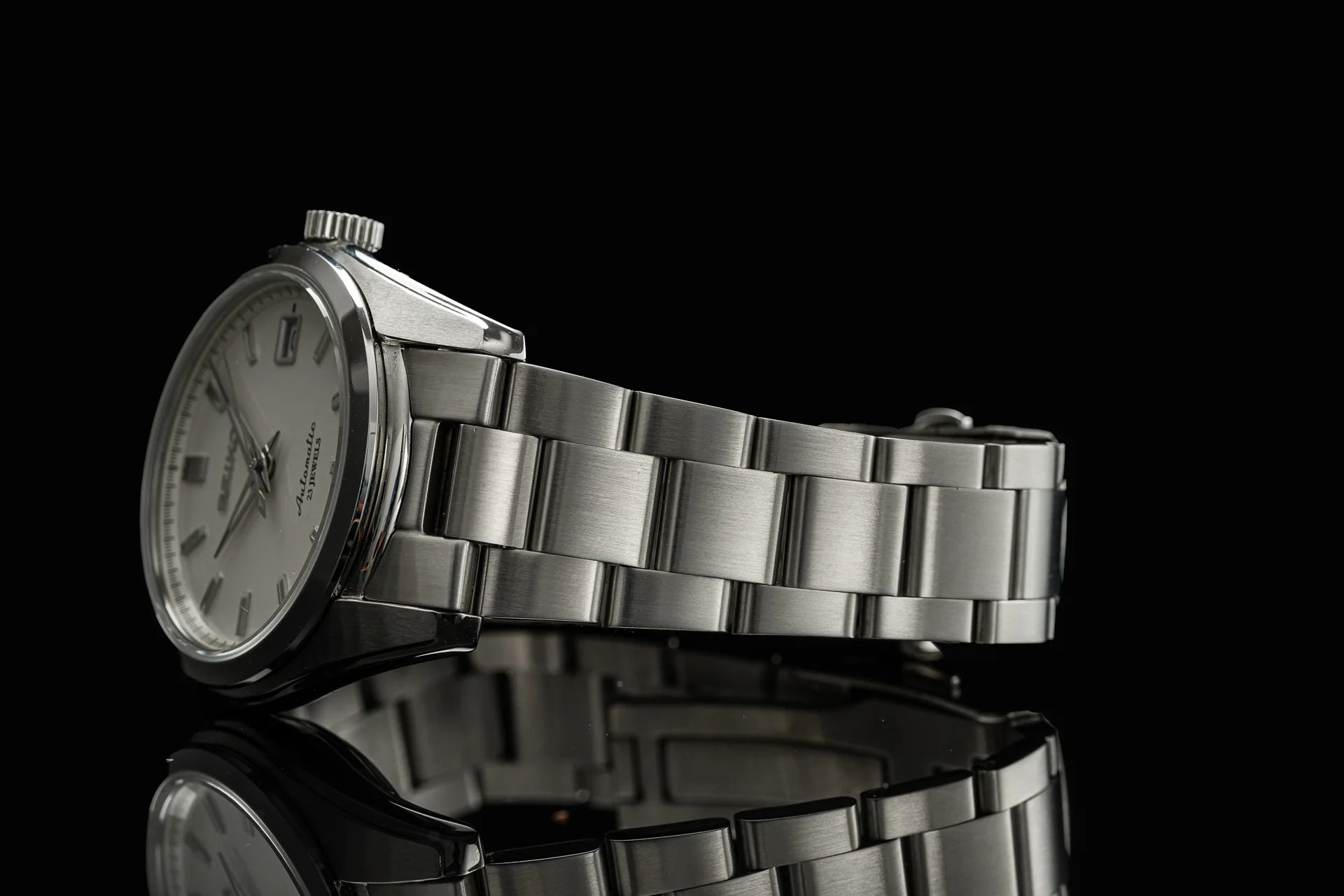 Silver stainless steel men's watch with cream dial and metal bracelet on black background