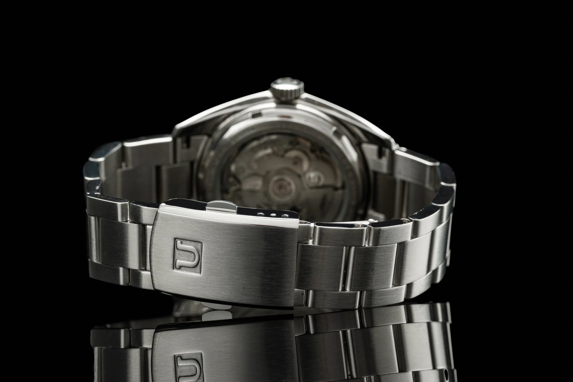 Stainless steel automatic watch with bracelet featuring Uncle Senator branding, transparent caseback showing mechanical movement on black background