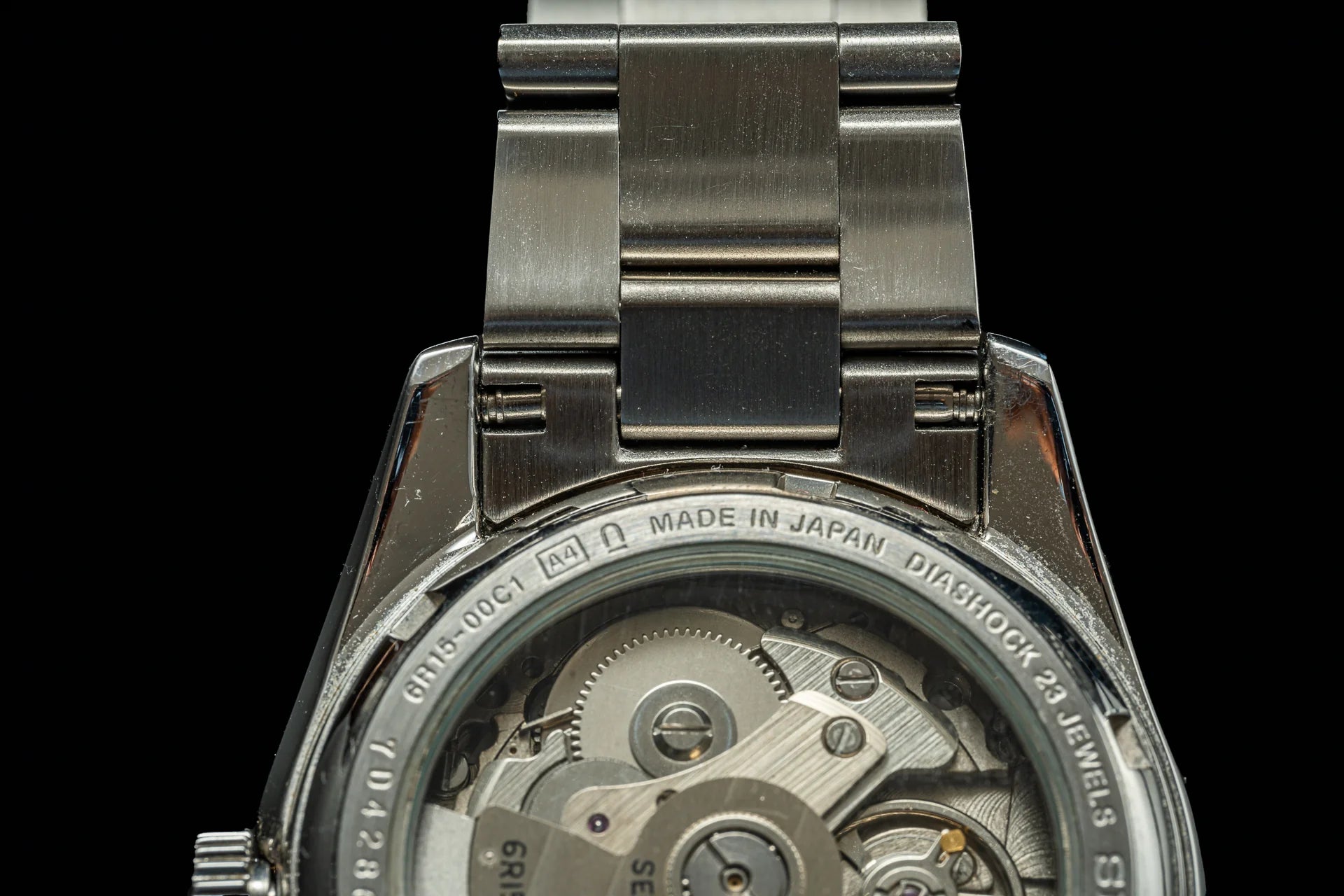 Seiko automatic watch with stainless steel bracelet showing exposed movement through exhibition caseback with visible gears