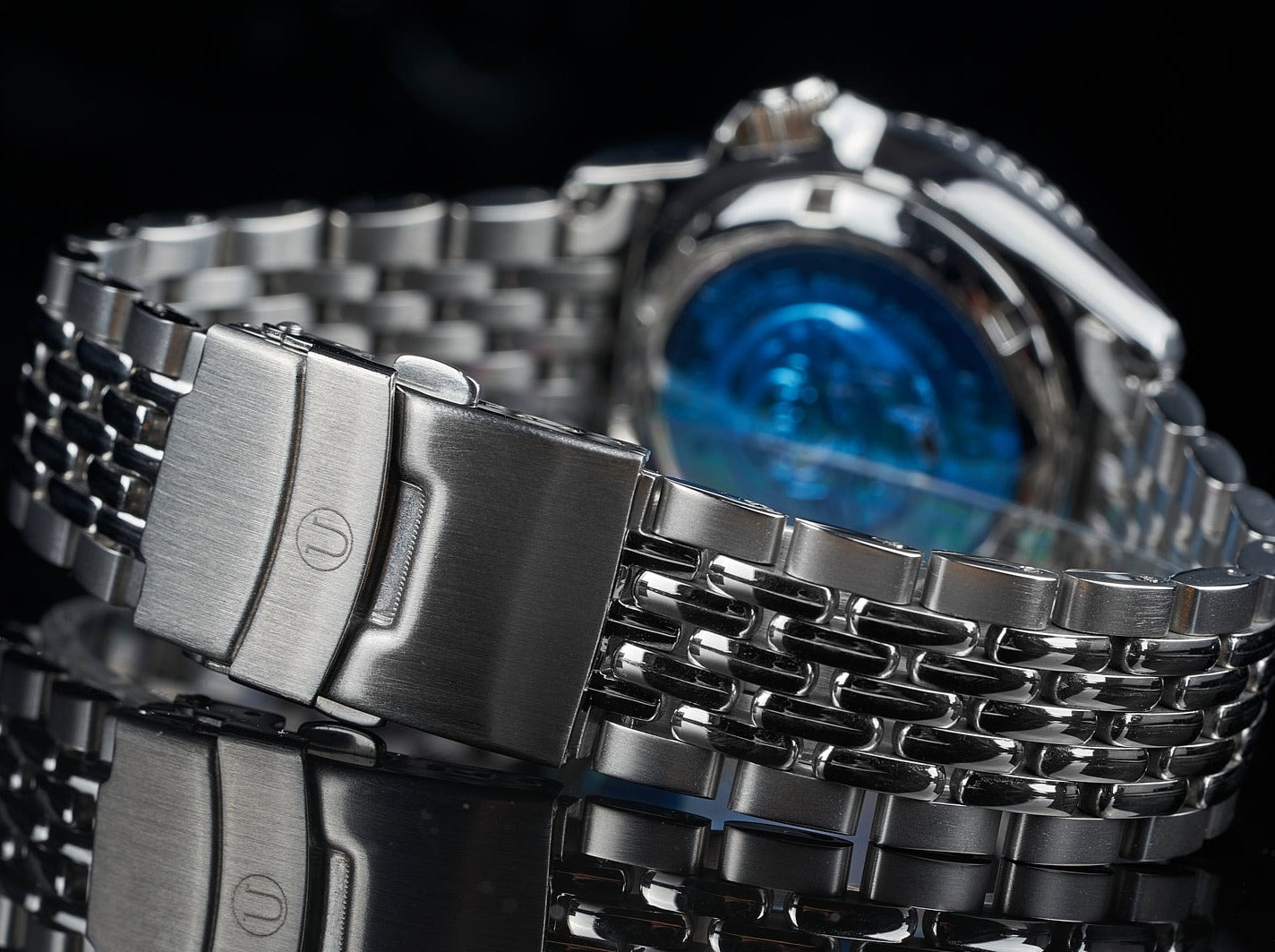 Stainless steel beads of rice bracelet on Seiko SKX013 dive watch with blue dial against black background