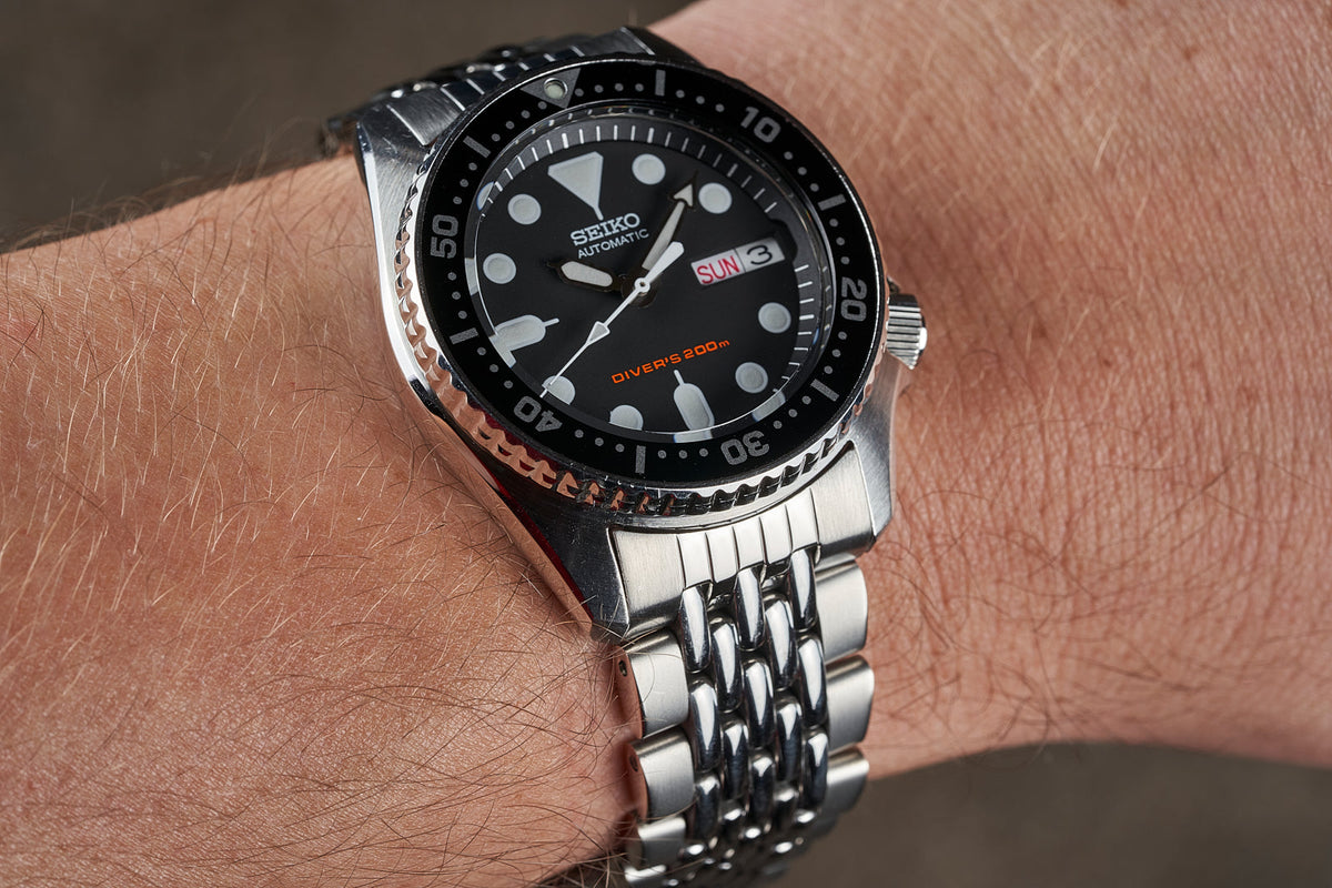 Seiko SKX013 automatic dive watch with black dial, stainless steel bracelet on wrist, 200m water resistant