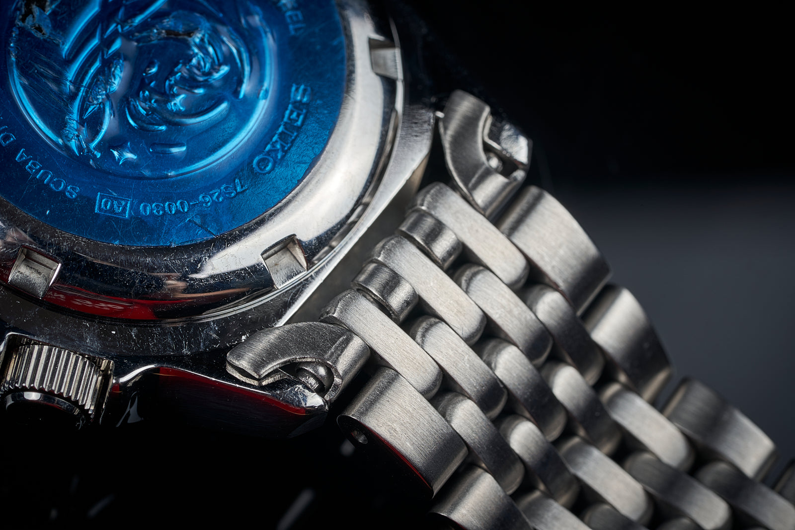 Seiko SKX013 dive watch with blue dial and stainless steel beads of rice bracelet detail on black background