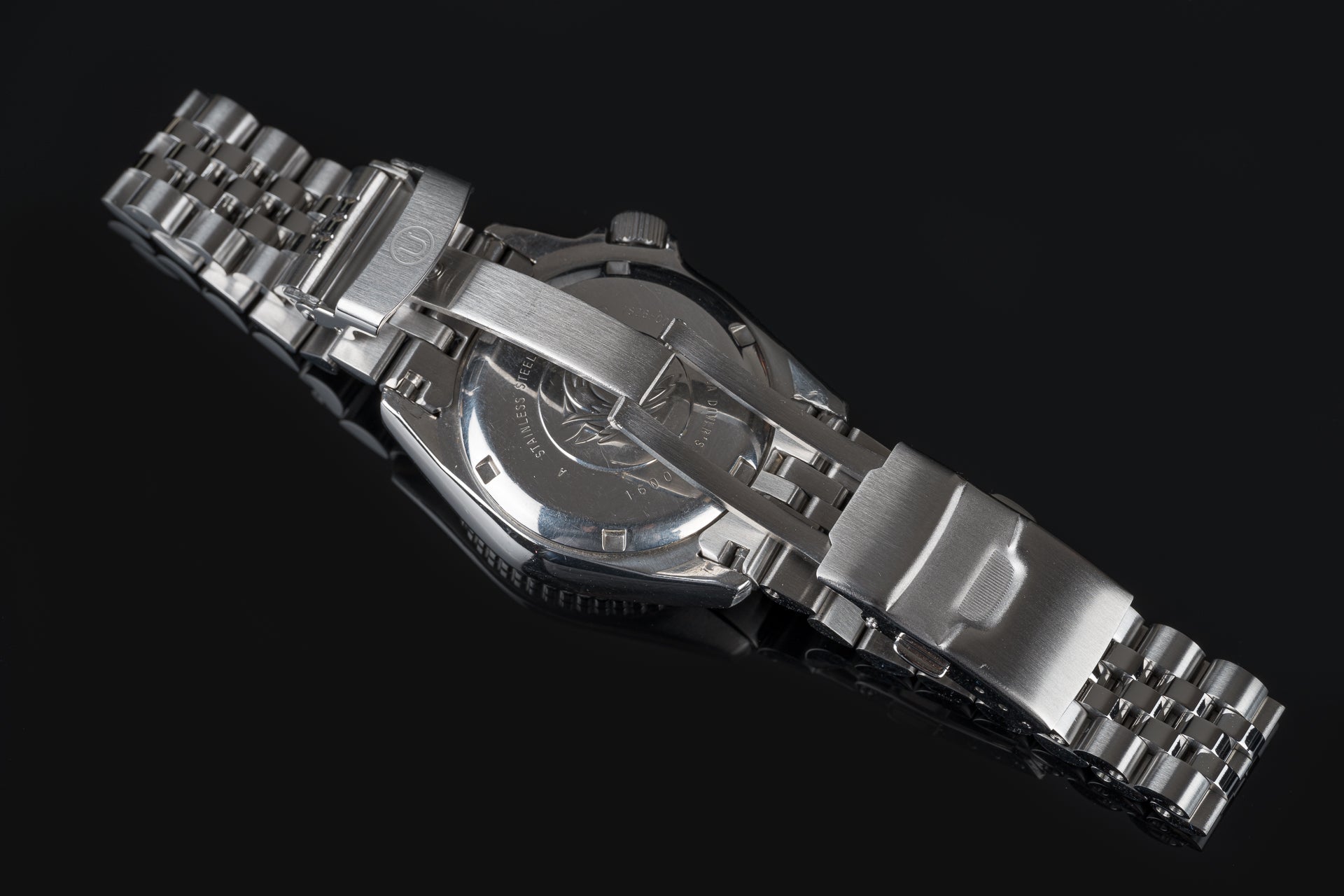 Stainless steel executive bracelet watch with metal link band and round dial on black background
