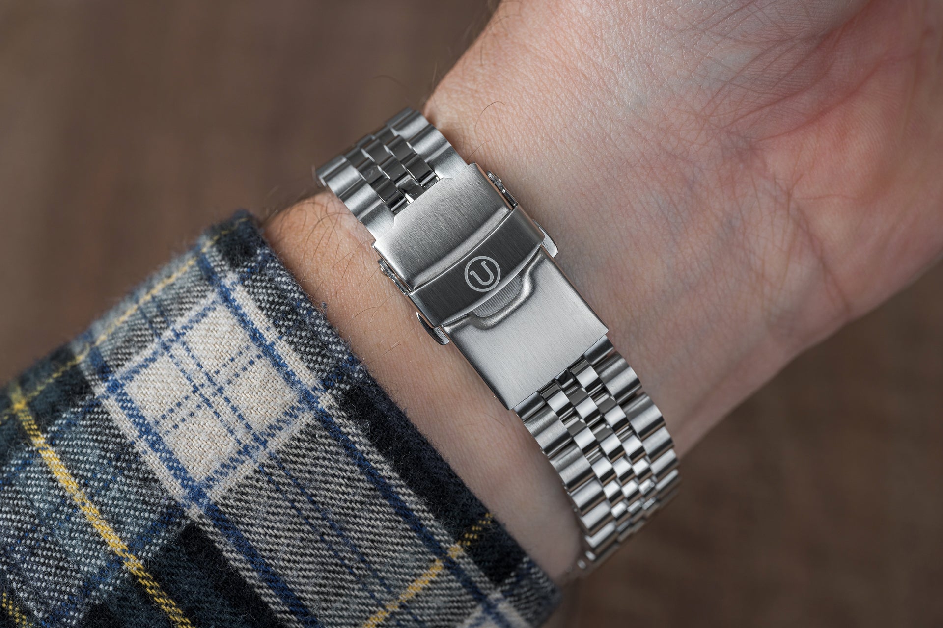 Stainless steel bracelet watch with metal link band worn on wrist, featuring brushed clasp and professional design
