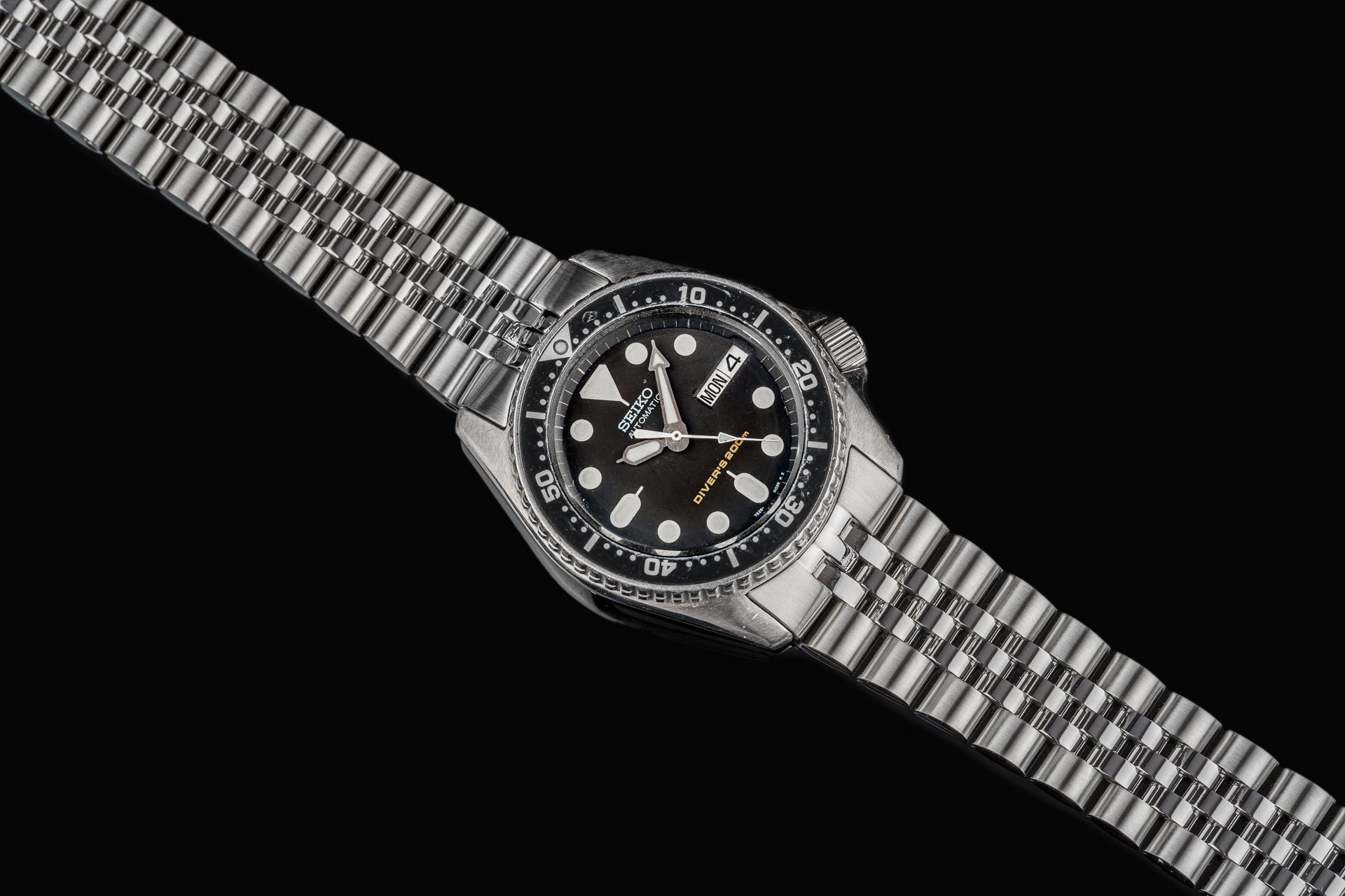 Seiko SKX013 dive watch with stainless steel bracelet and black dial featuring white dot markers and day-date window
