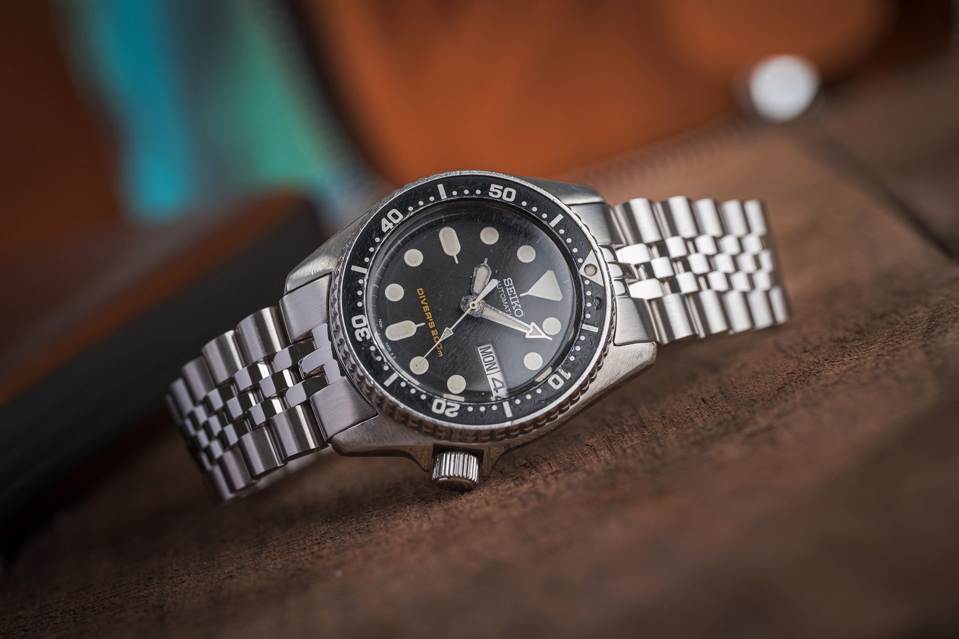 Seiko SKX013 executive dive watch with black dial, stainless steel bracelet and rotating bezel on brown surface