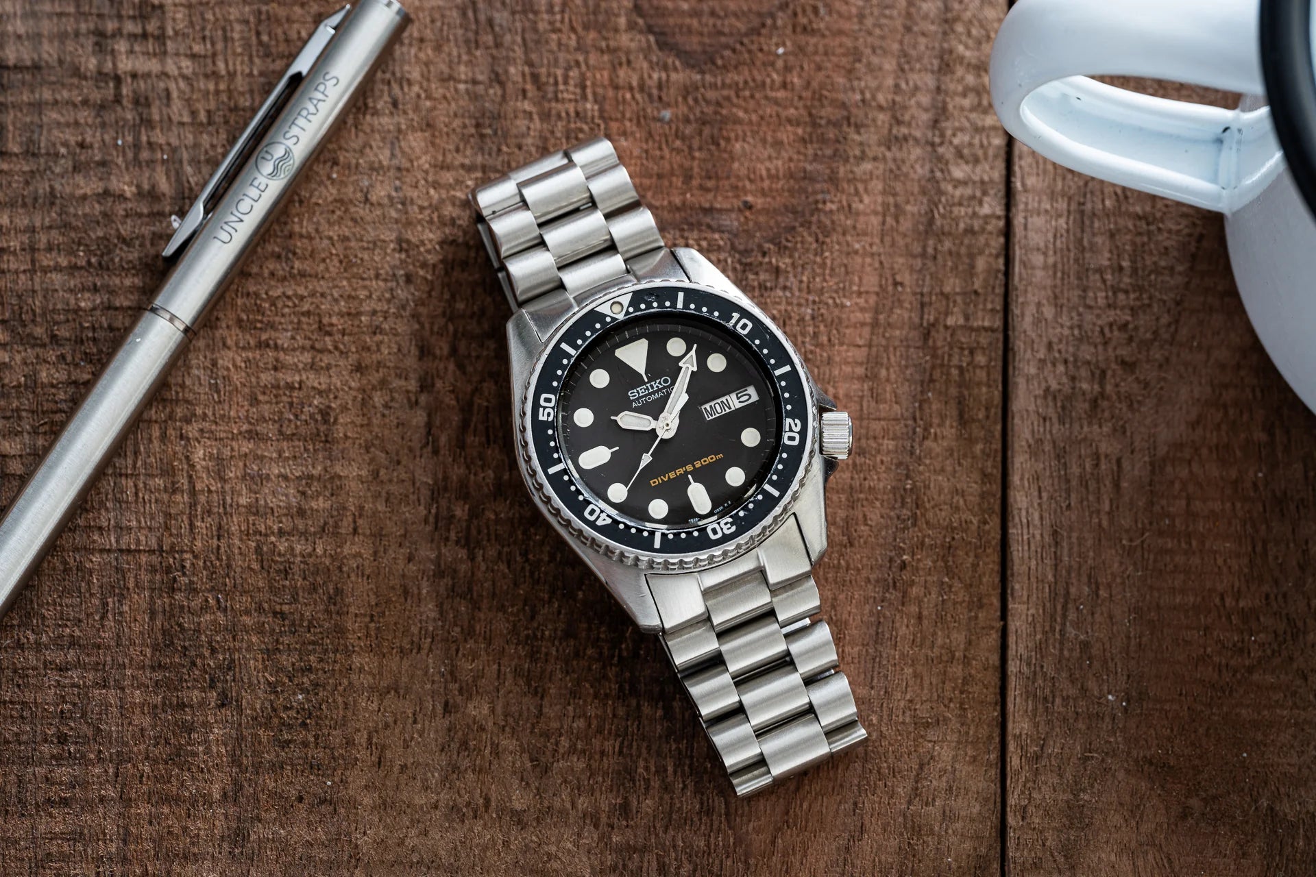 Seiko SKX013 stainless steel dive watch with black dial and day-date window on wooden surface