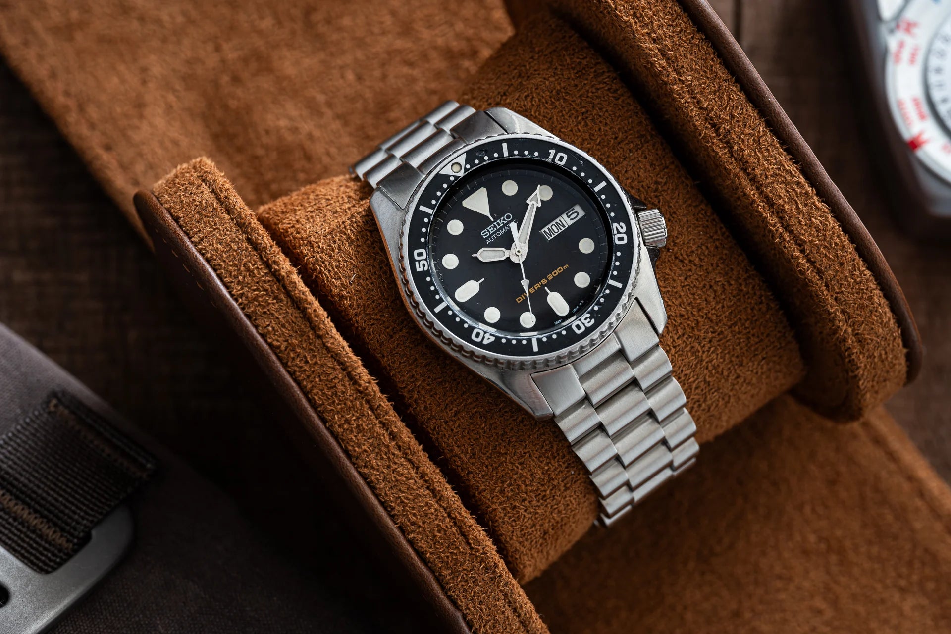 Seiko SKX013 dive watch with black dial, stainless steel bracelet and bezel on brown suede fabric