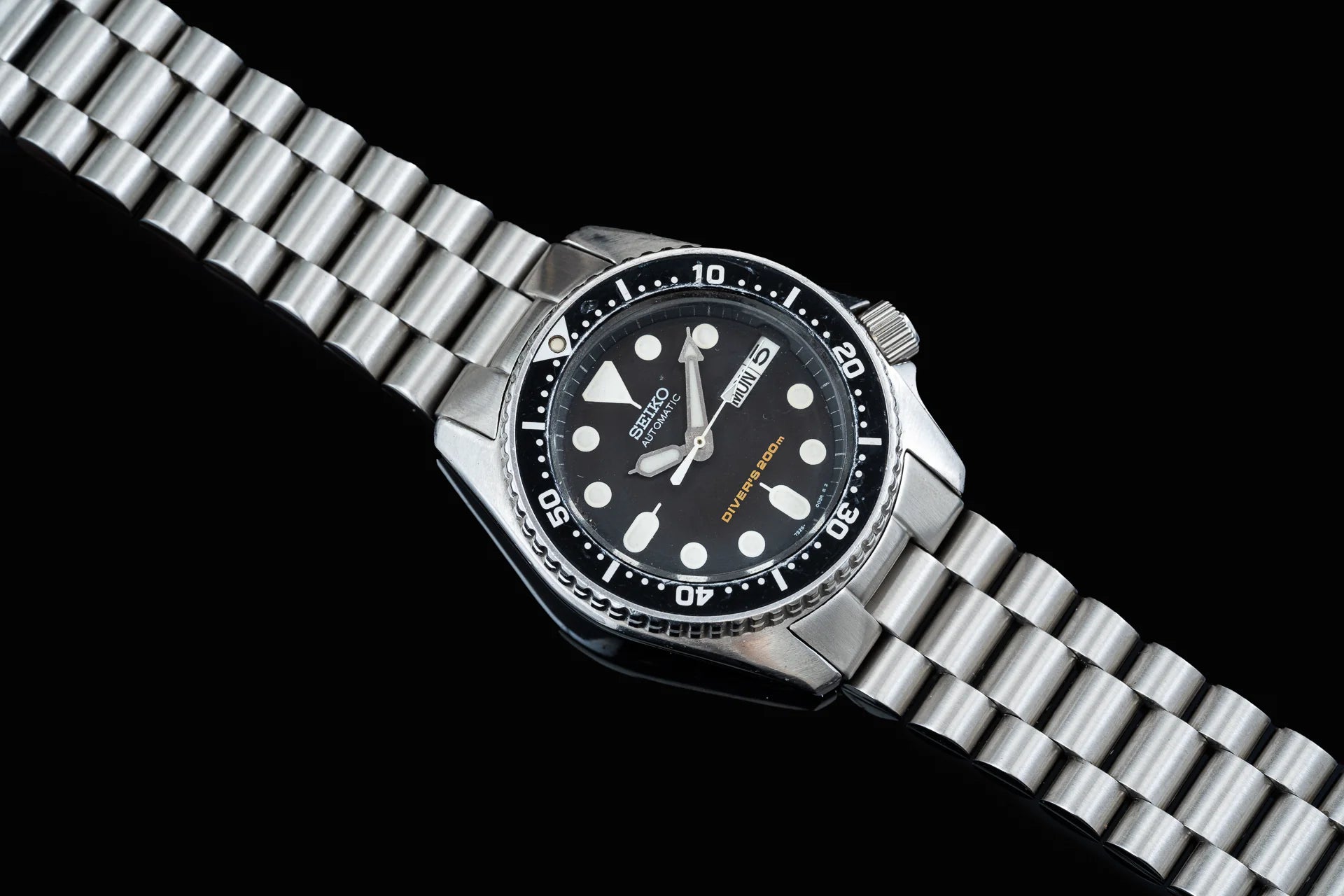 Seiko SKX013 stainless steel dive watch with black dial, white hour markers, day-date window, rotating bezel, and steel bracelet
