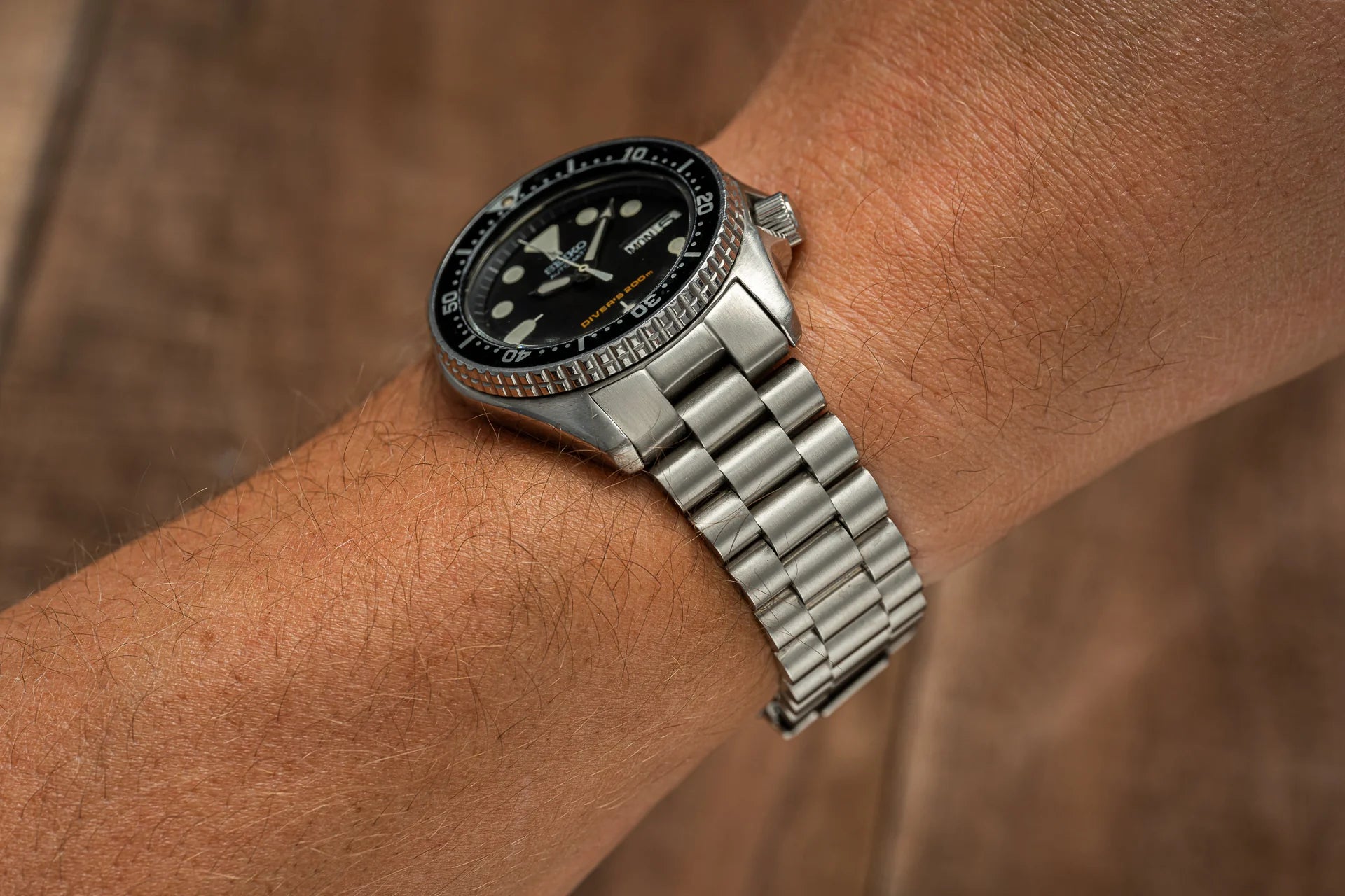 Seiko SKX013 dive watch with black dial and rotating bezel on stainless steel bracelet, worn on wrist