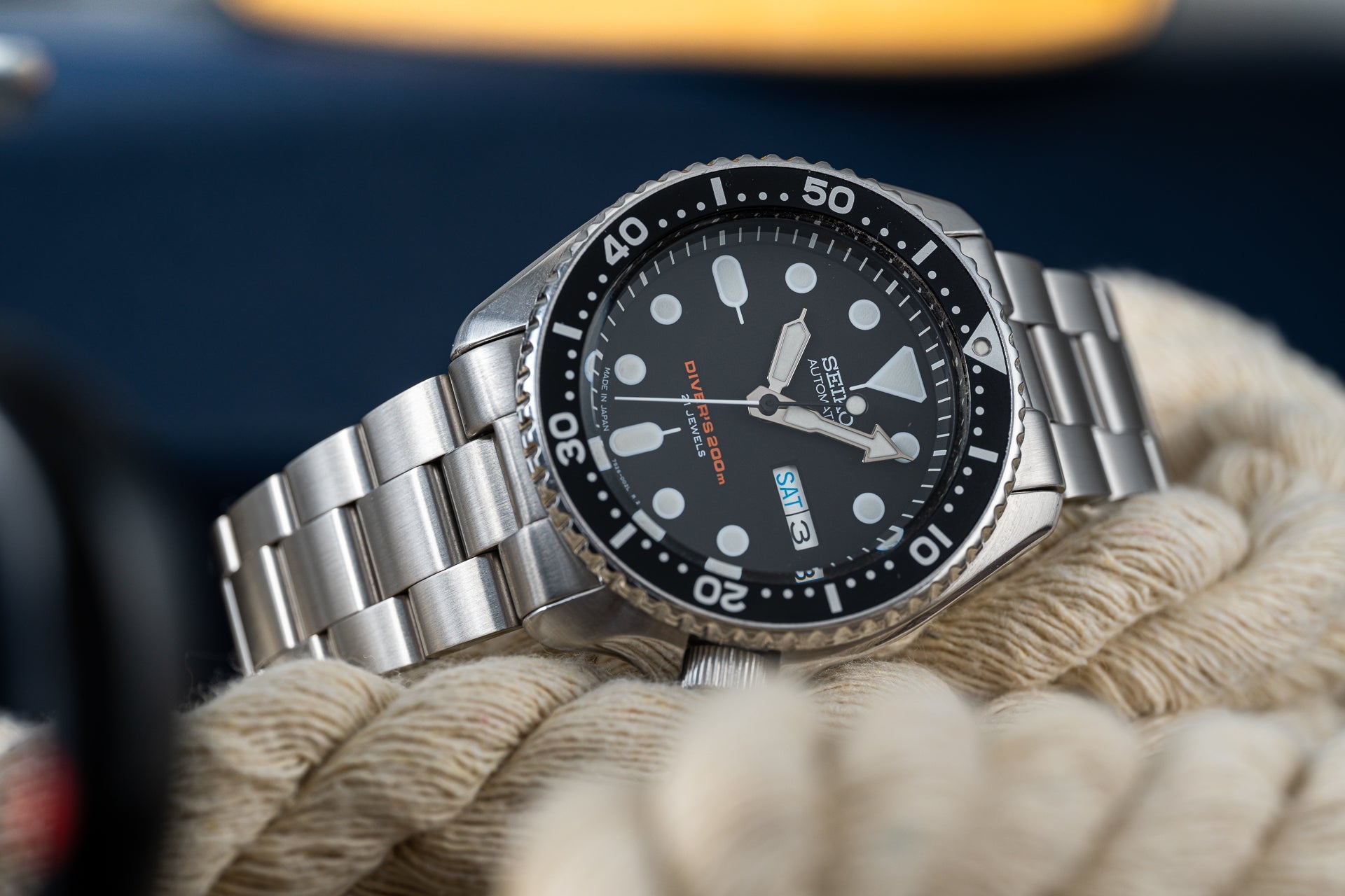 Seiko SKX007 stainless steel dive watch with black dial and rotating bezel on white rope, professional timepiece