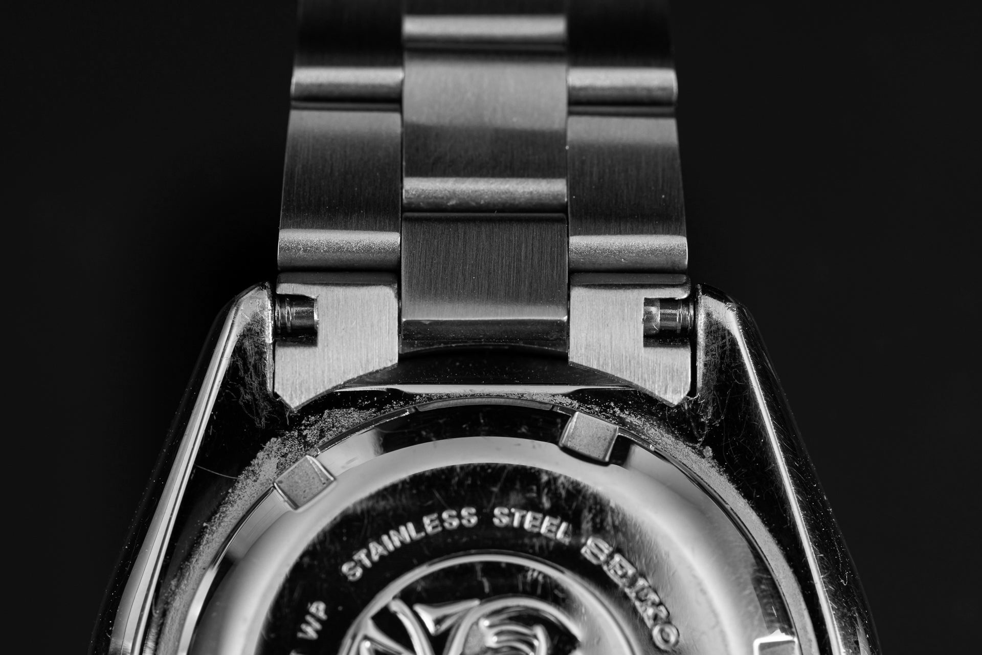 Stainless steel watch bracelet and caseback detail for Seiko SKX007 dive watch showing brushed metal links and engraved text