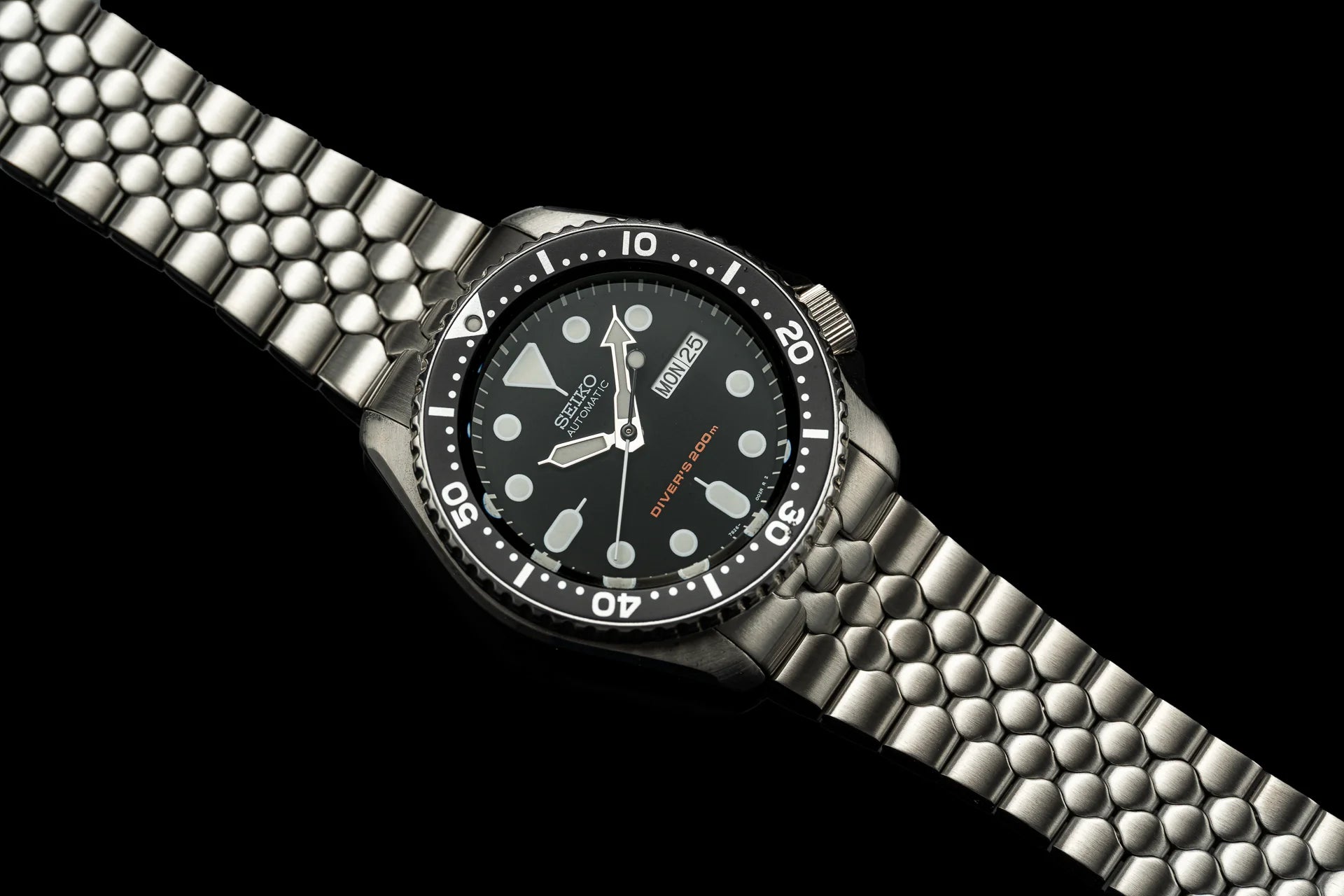 Seiko SKX007 automatic dive watch with stainless steel jubilee bracelet and black dial on black background