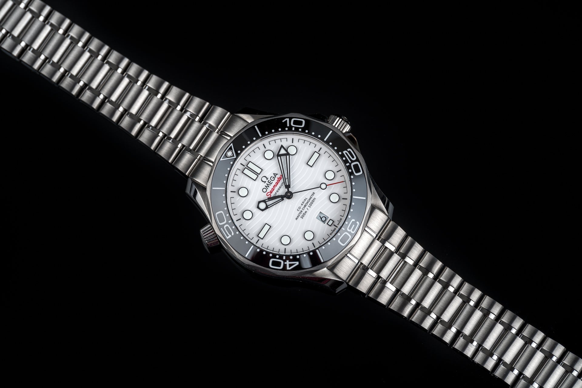 Omega Seamaster 300M professional diving watch with white dial, stainless steel bracelet and black ceramic bezel on black background