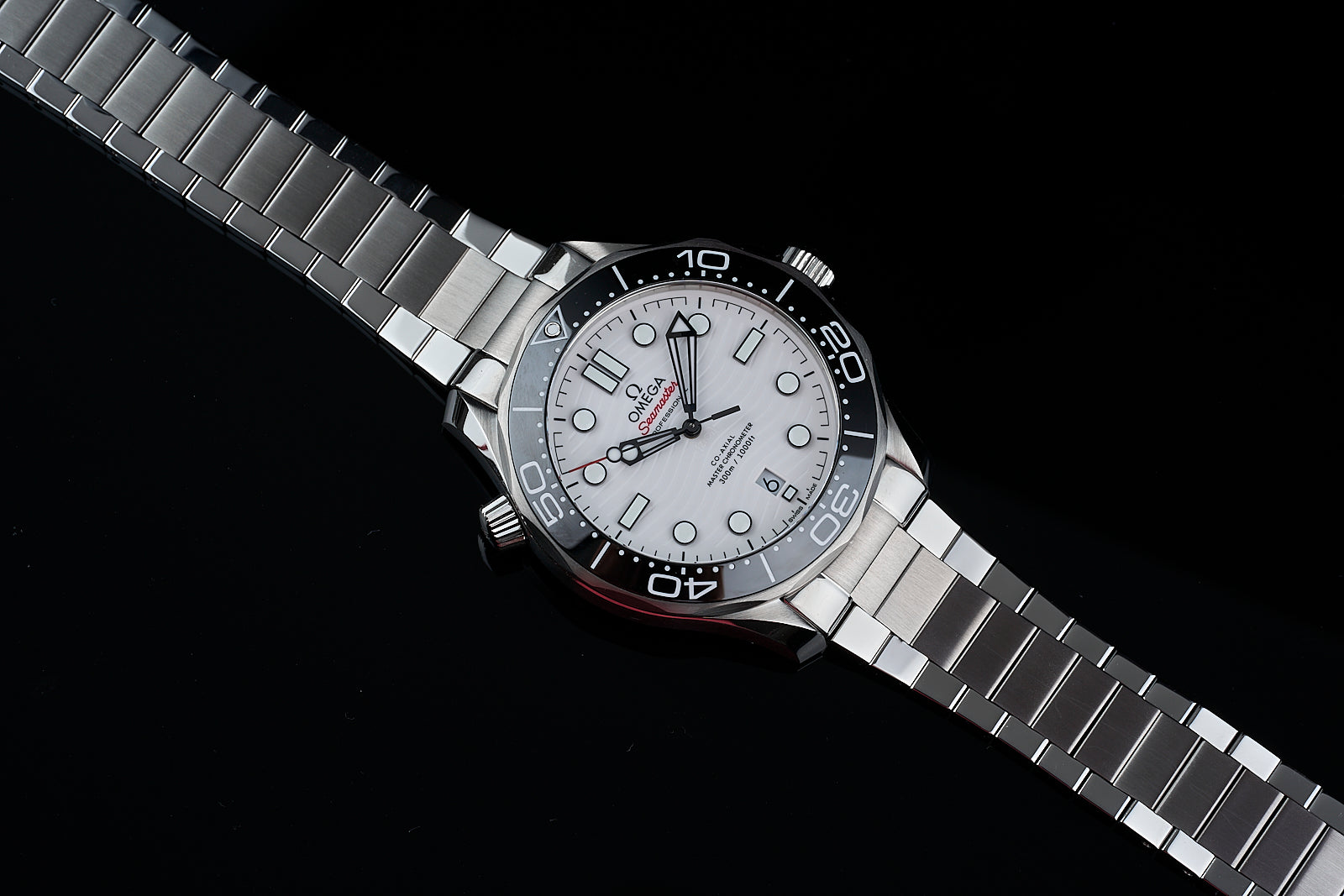 Silver stainless steel sports watch with white dial, black bezel, and matching metal bracelet on black background