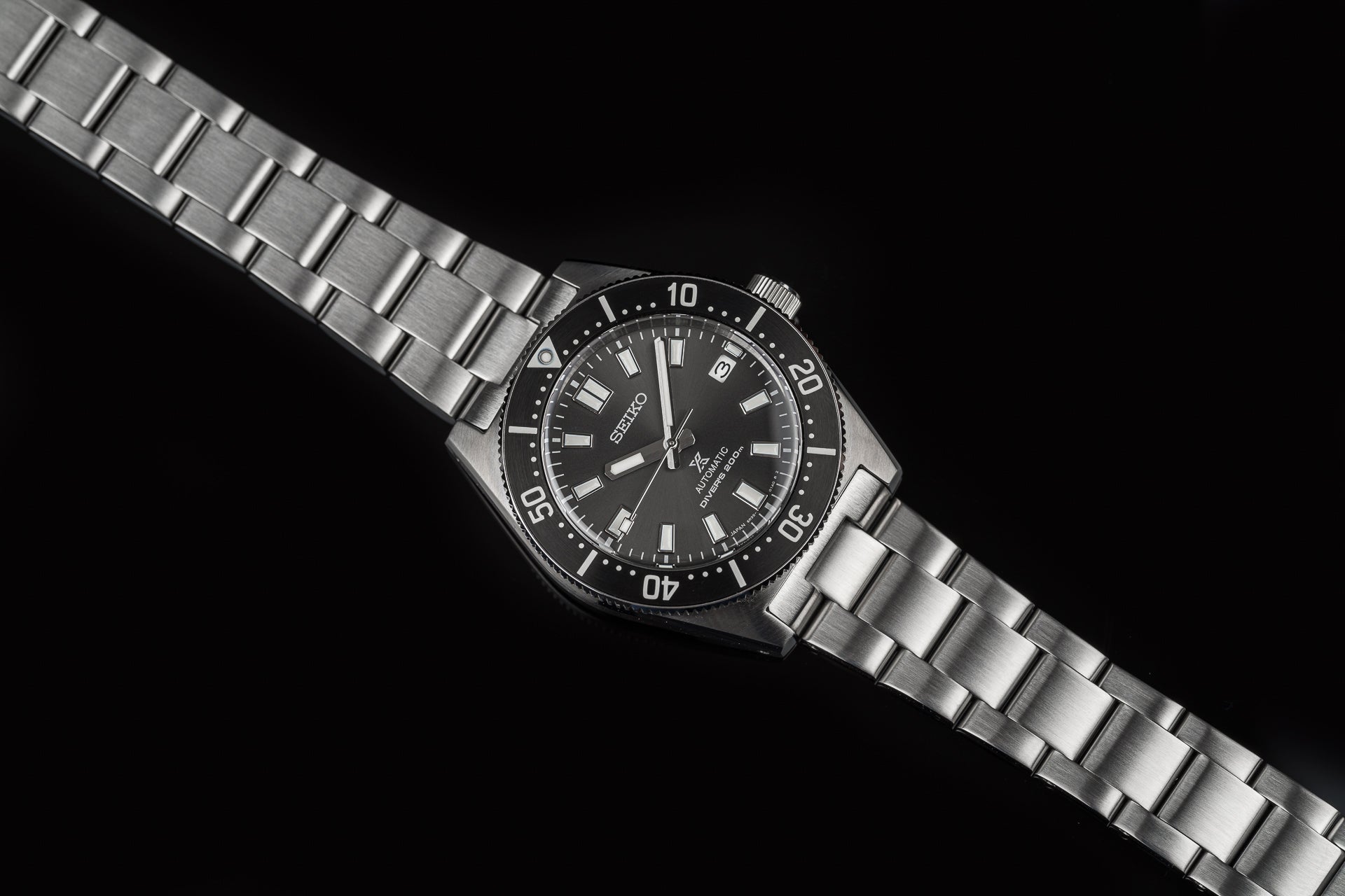 Seiko Prospex automatic diver watch with stainless steel bracelet and black dial on black background