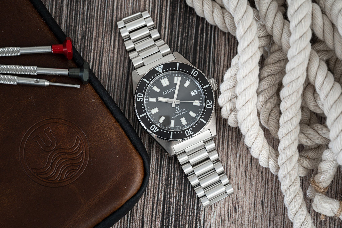 Seiko SPB143 62MAS automatic diving watch with stainless steel bracelet and black dial on rope and leather background