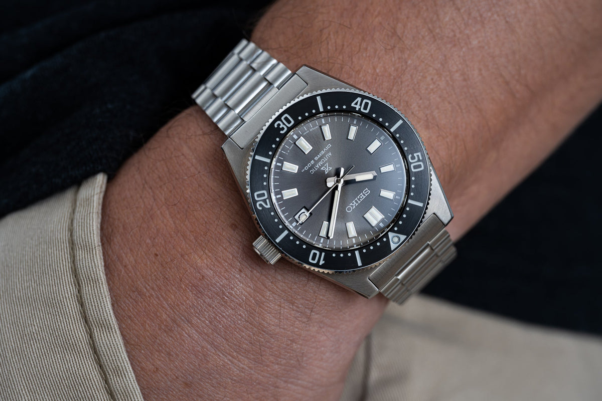 Stainless steel dive watch with black dial, rotating bezel, and matching metal bracelet worn on wrist