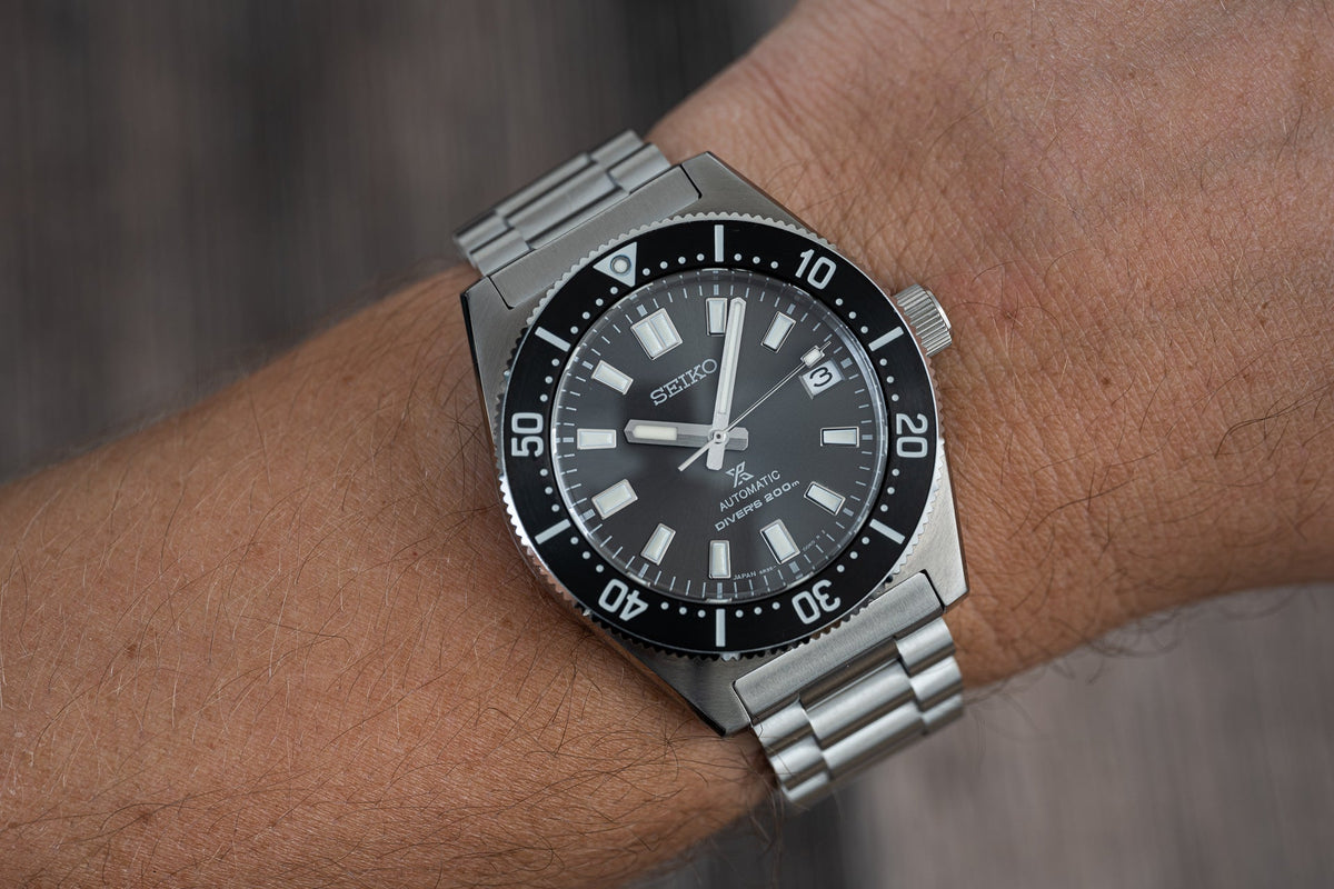 Seiko automatic dive watch with stainless steel bracelet, black dial and rotating bezel worn on wrist