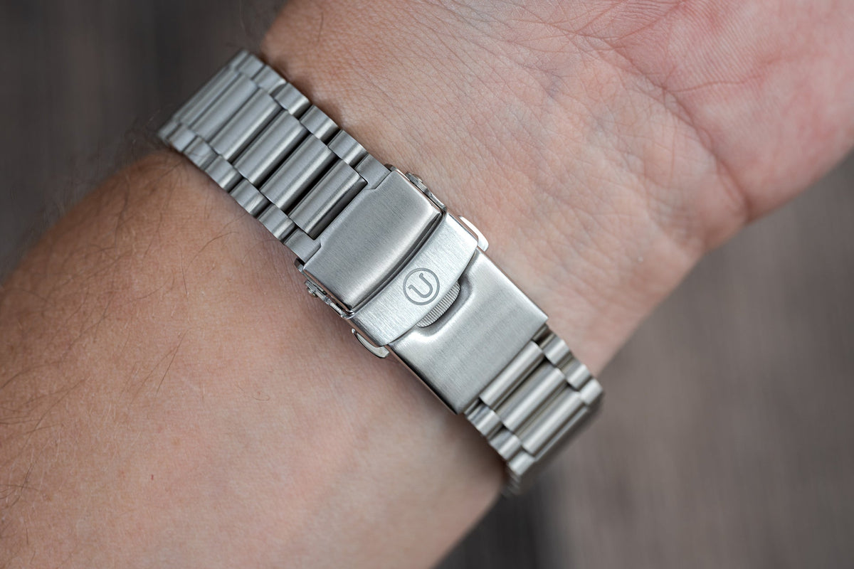 Stainless steel watch bracelet with solid links and deployant clasp worn on wrist