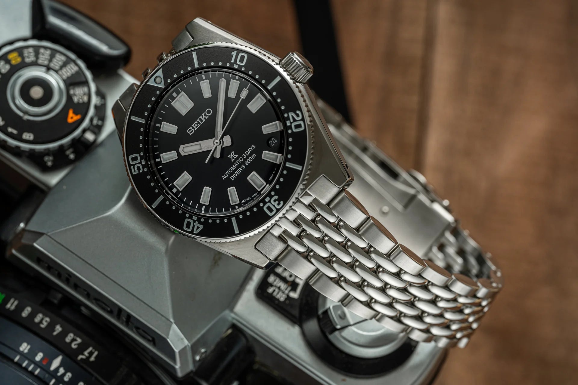 Seiko SPB45 automatic dive watch with black dial, stainless steel beads of rice bracelet, and 300m water resistance on camera background