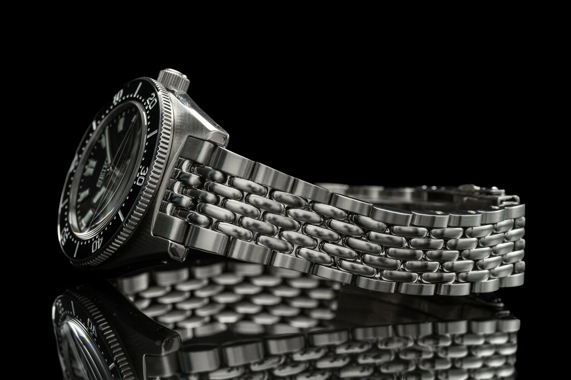 Seiko SPB45x dive watch with stainless steel beads of rice bracelet on black background, showcasing detailed link design and rotating bezel