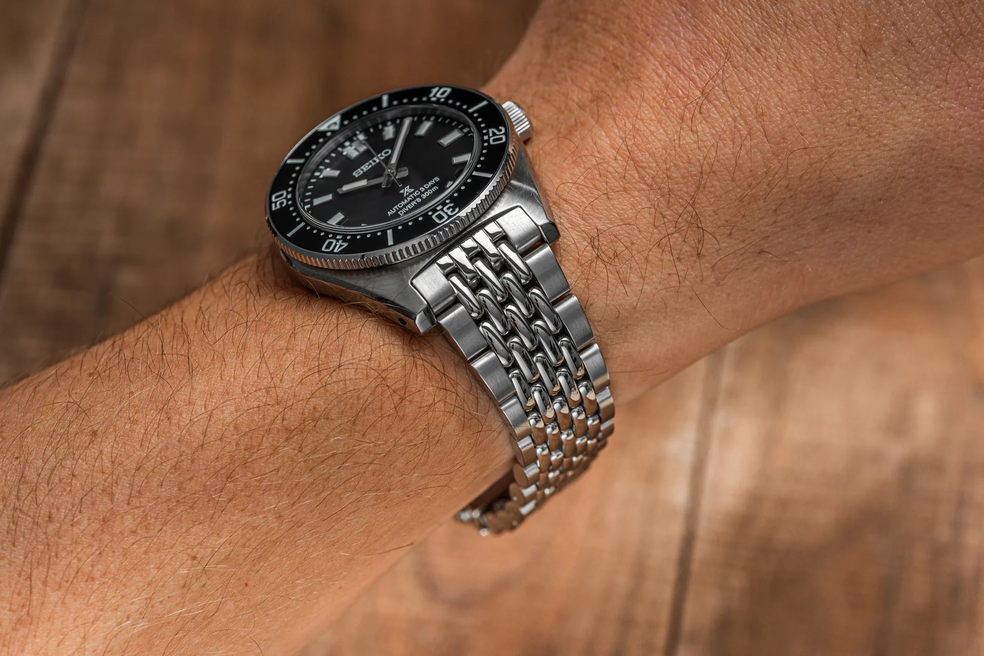 Seiko SPB45x dive watch with black dial and stainless steel beads of rice bracelet worn on wrist