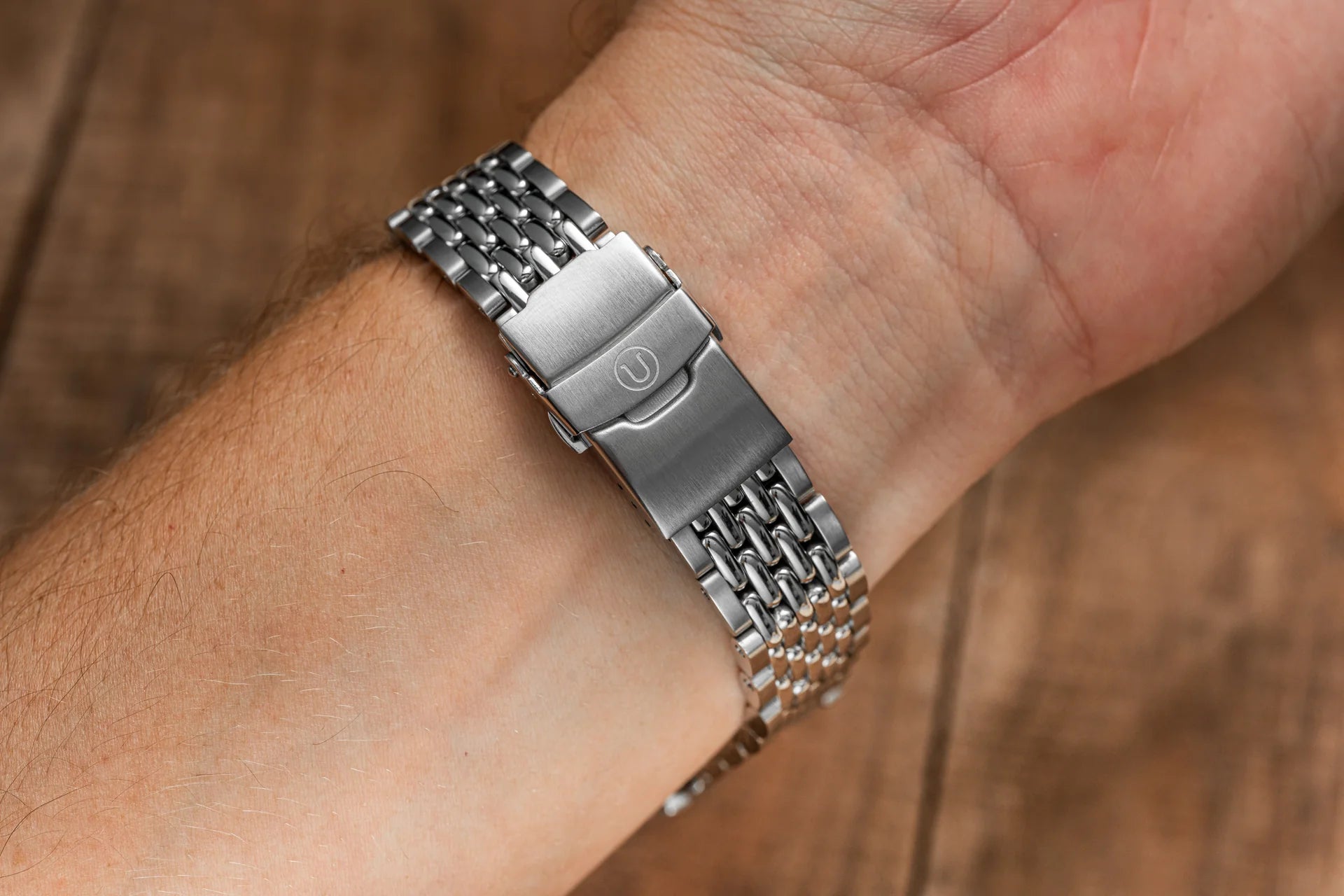 Stainless steel beads of rice watch bracelet with solid links and fold-over clasp worn on wrist