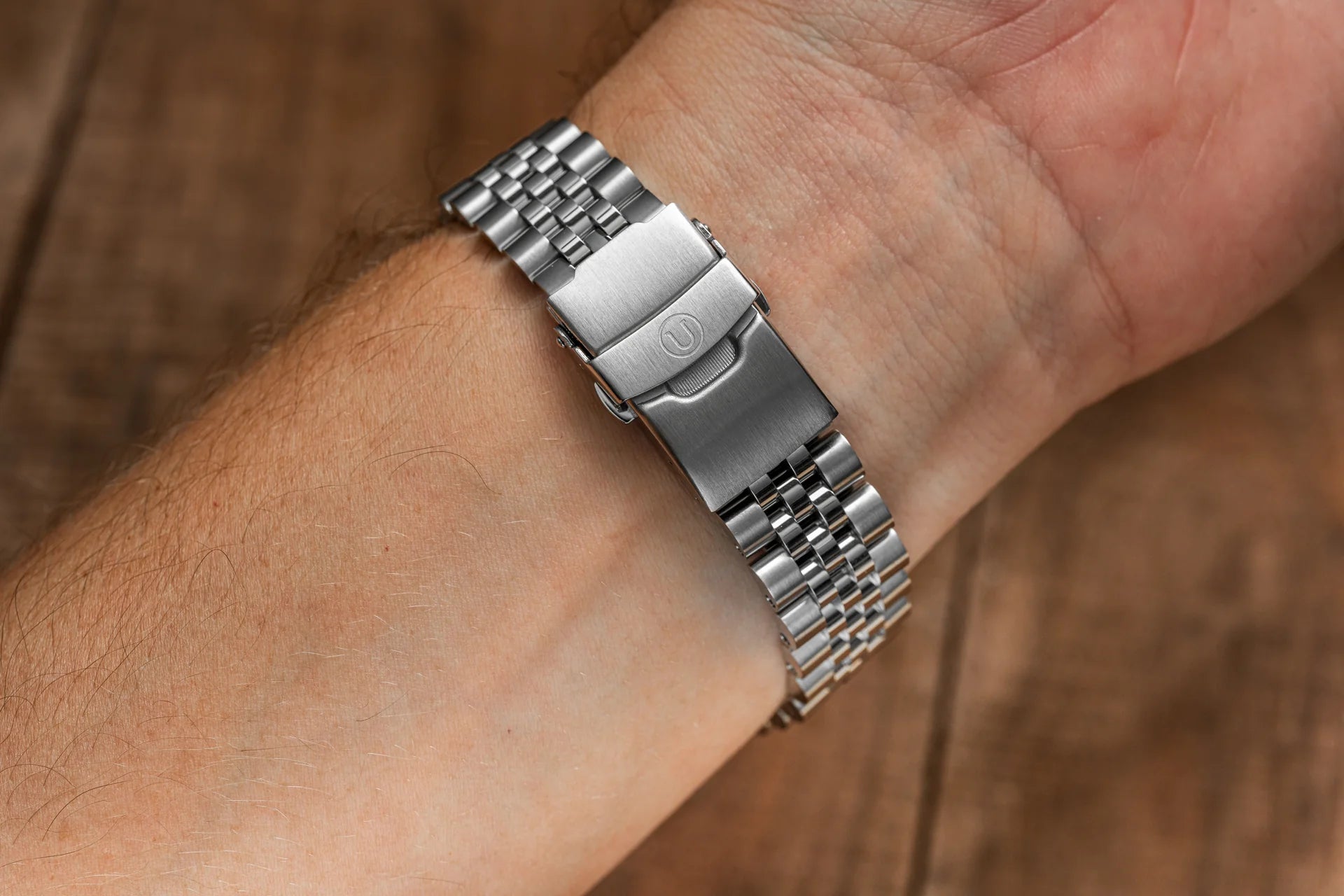 Stainless steel watch bracelet with solid links and deployant clasp worn on wrist, professional metal watch band replacement