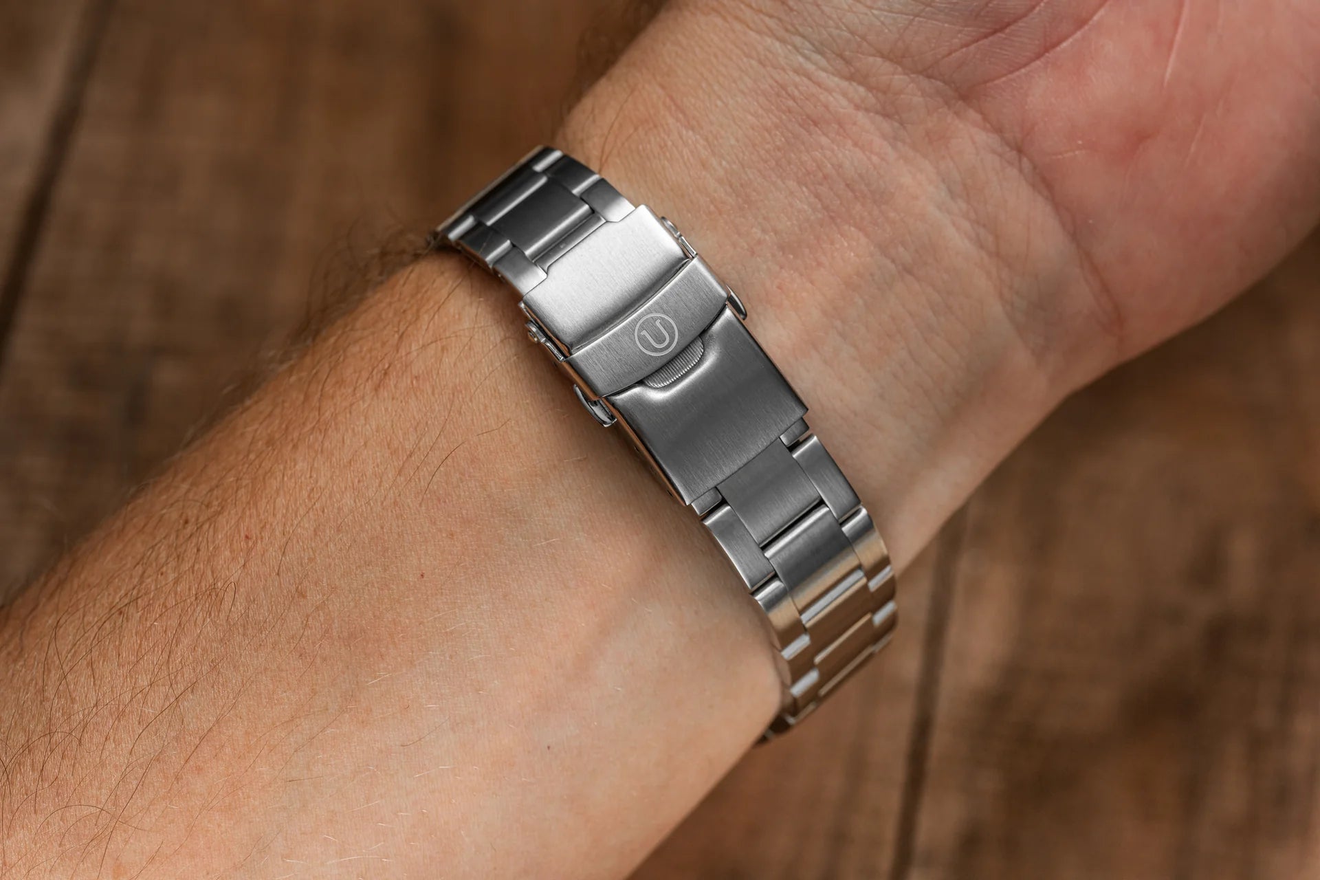 Stainless steel watch bracelet with solid end links and push-button clasp worn on wrist