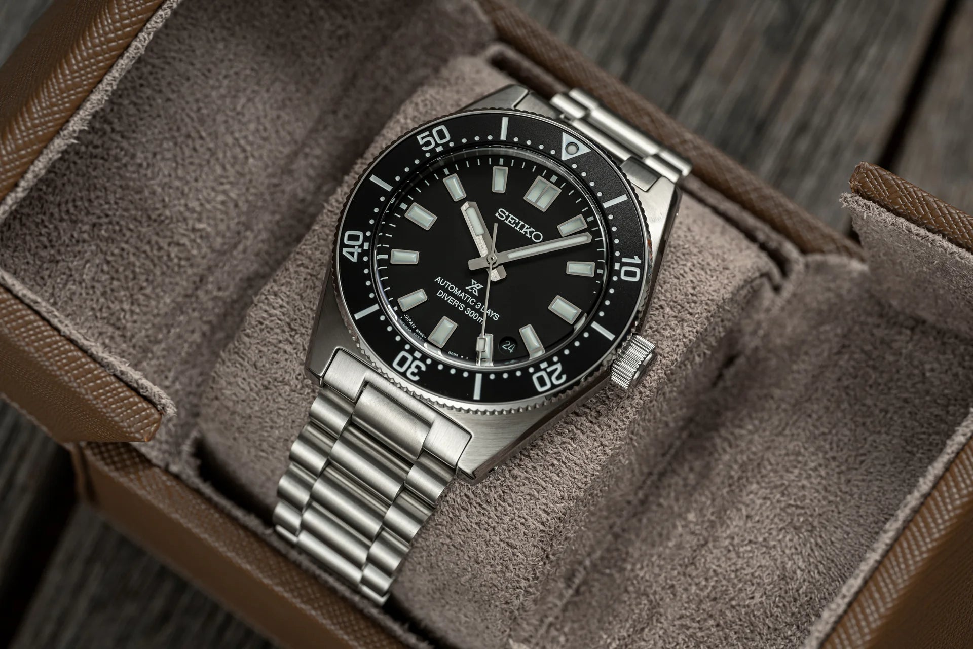Seiko Prospex automatic diver watch with black dial, stainless steel bracelet, displayed on gray fabric watch roll