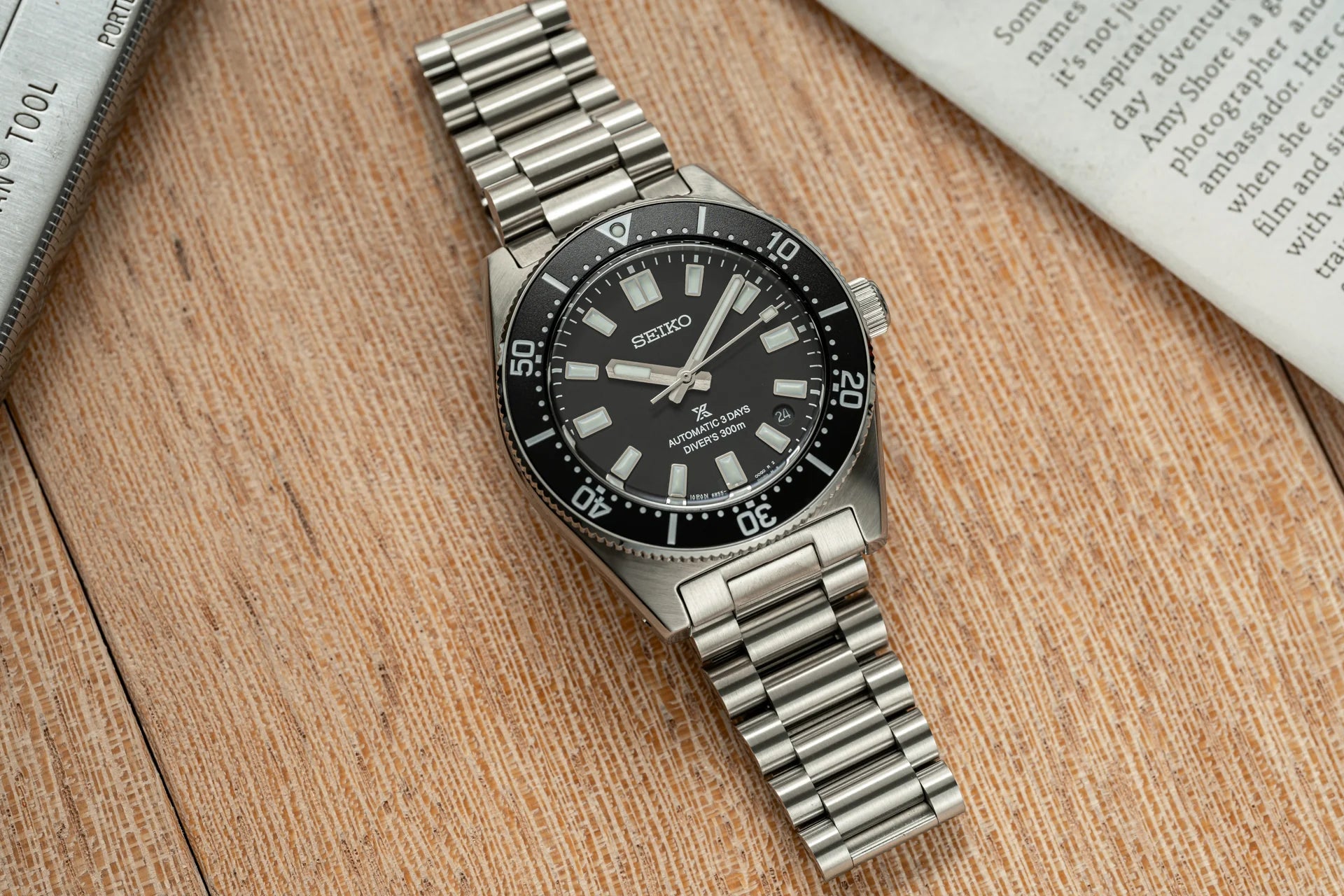 Seiko automatic dive watch with black dial, stainless steel bracelet and rotating bezel, displayed on wooden surface