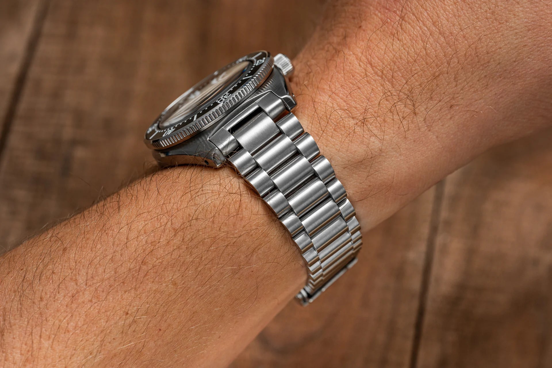 Stainless steel dive watch with Lincoln bracelet worn on wrist showing polished metal links and rotating bezel