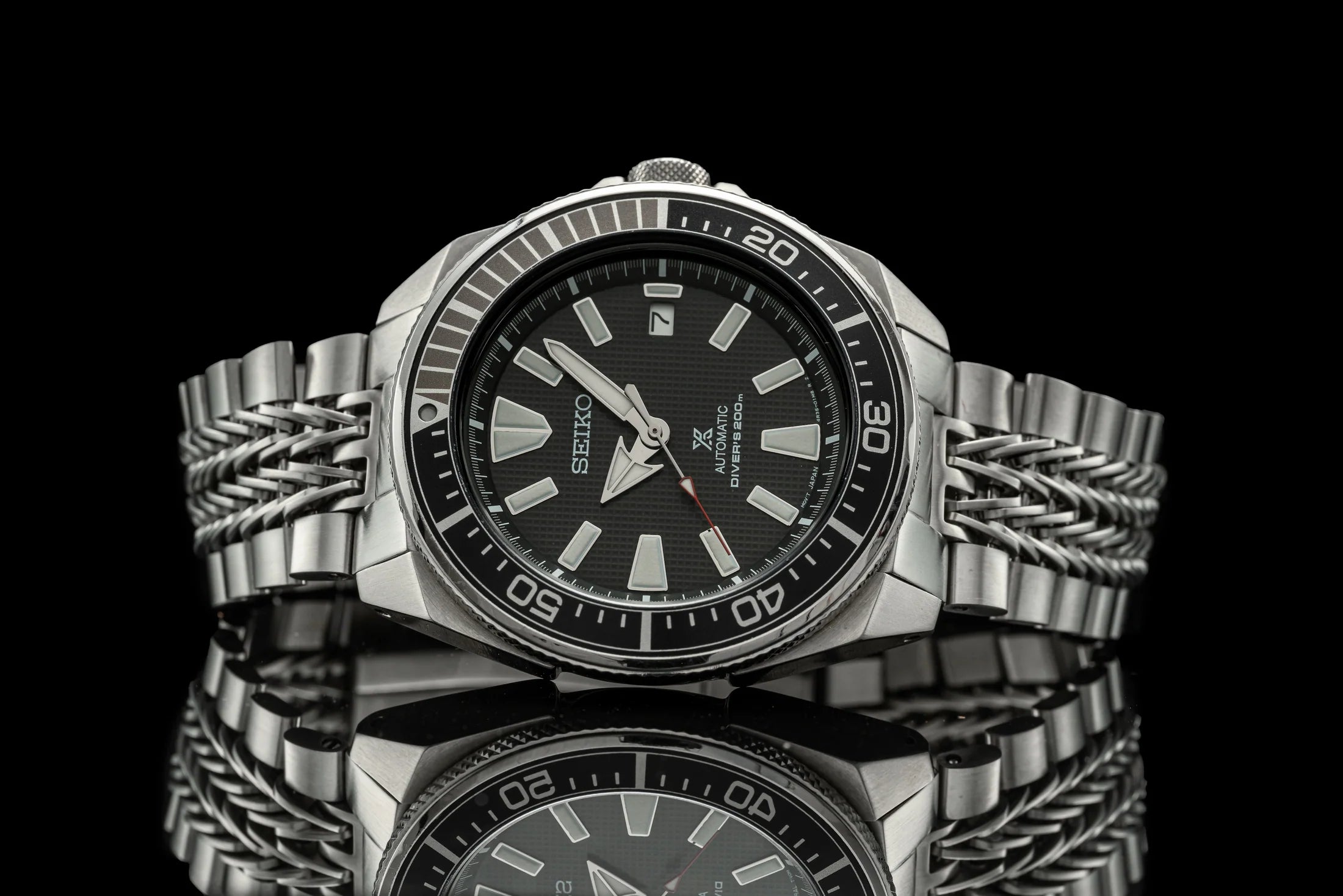 Seiko Prospex Samurai stainless steel diver watch with black dial, applied indices, and matching metal bracelet on black background