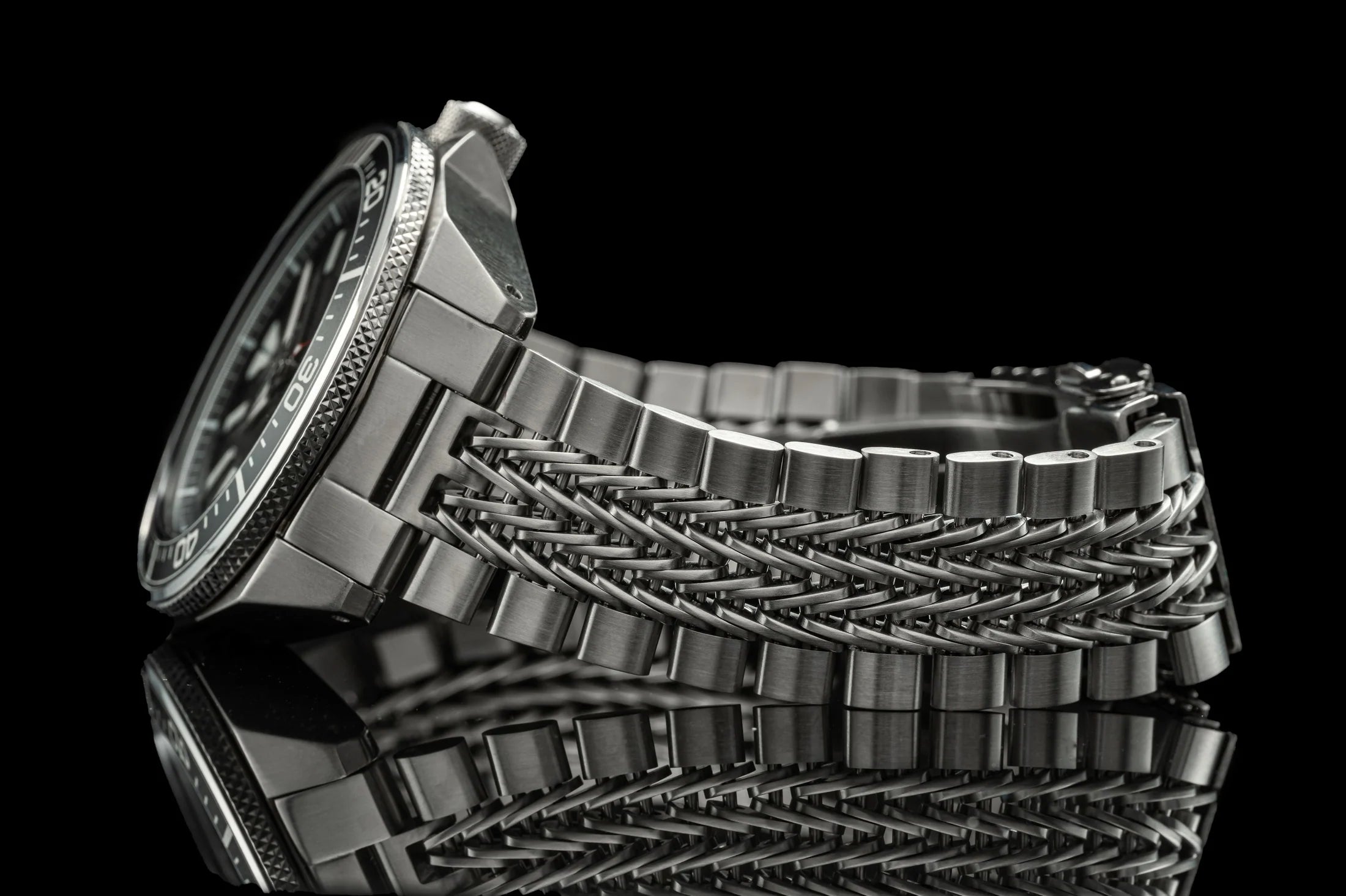Stainless steel dive watch with braided metal bracelet and rotating bezel, black background