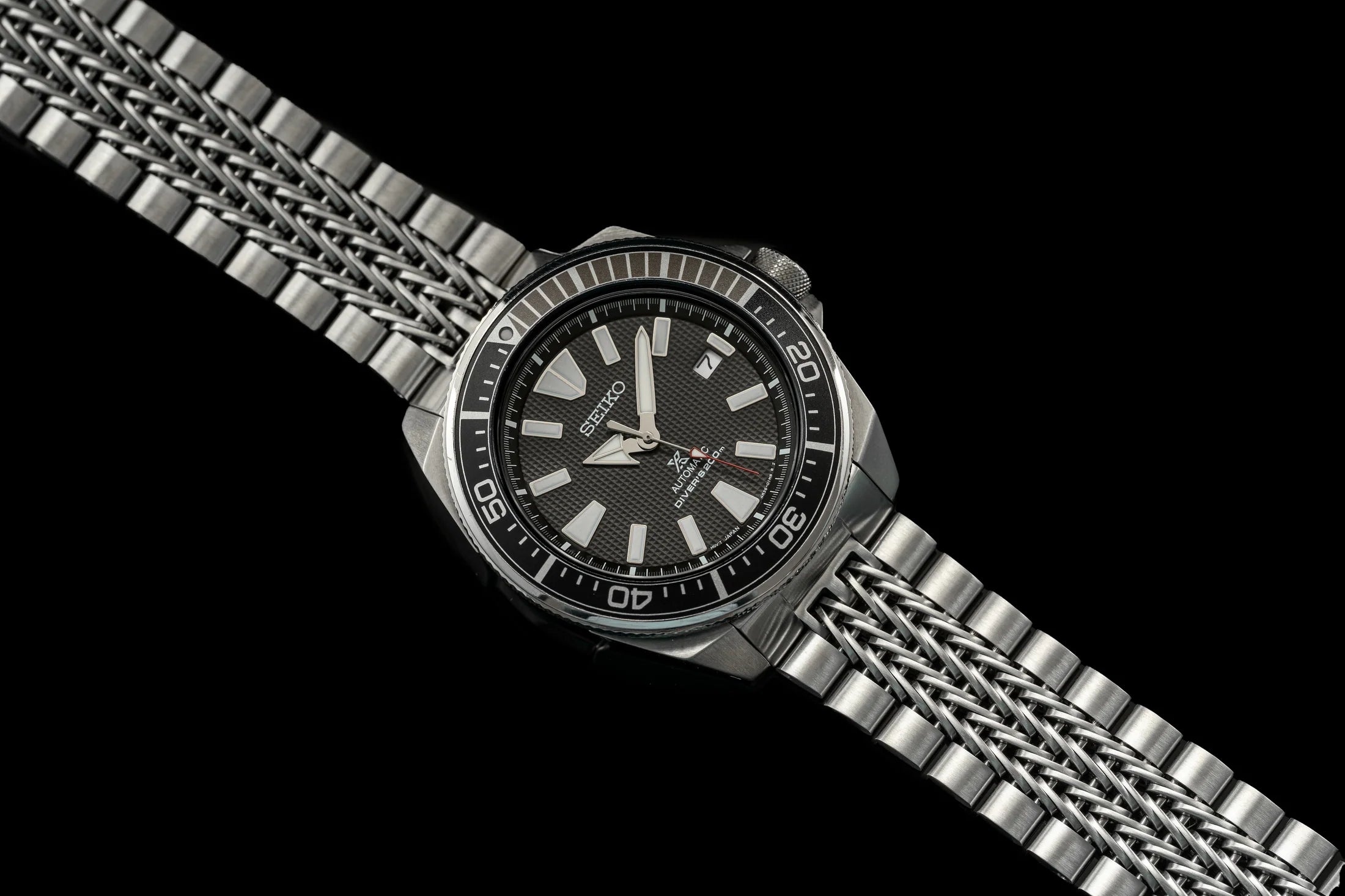 Seiko Samurai stainless steel dive watch with black dial, date window, and razor-wire metal bracelet on black background
