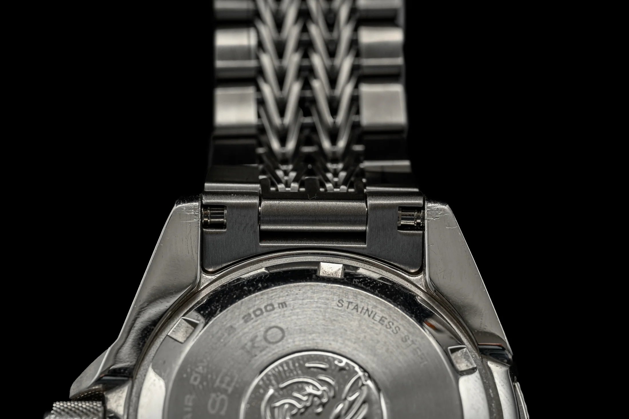 Stainless steel military watch with razor-wire design bracelet, showing polished case back with 300m water resistance rating