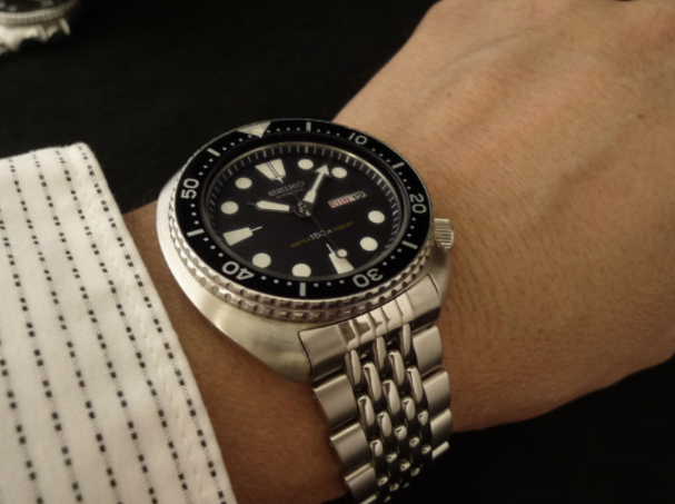 Seiko 6309 dive watch with stainless steel beads of rice bracelet and black dial on wrist